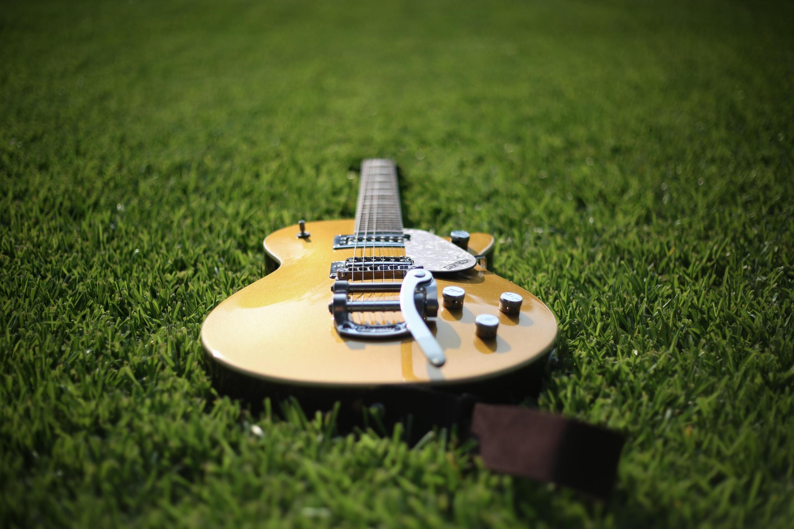 brown guitar on grass