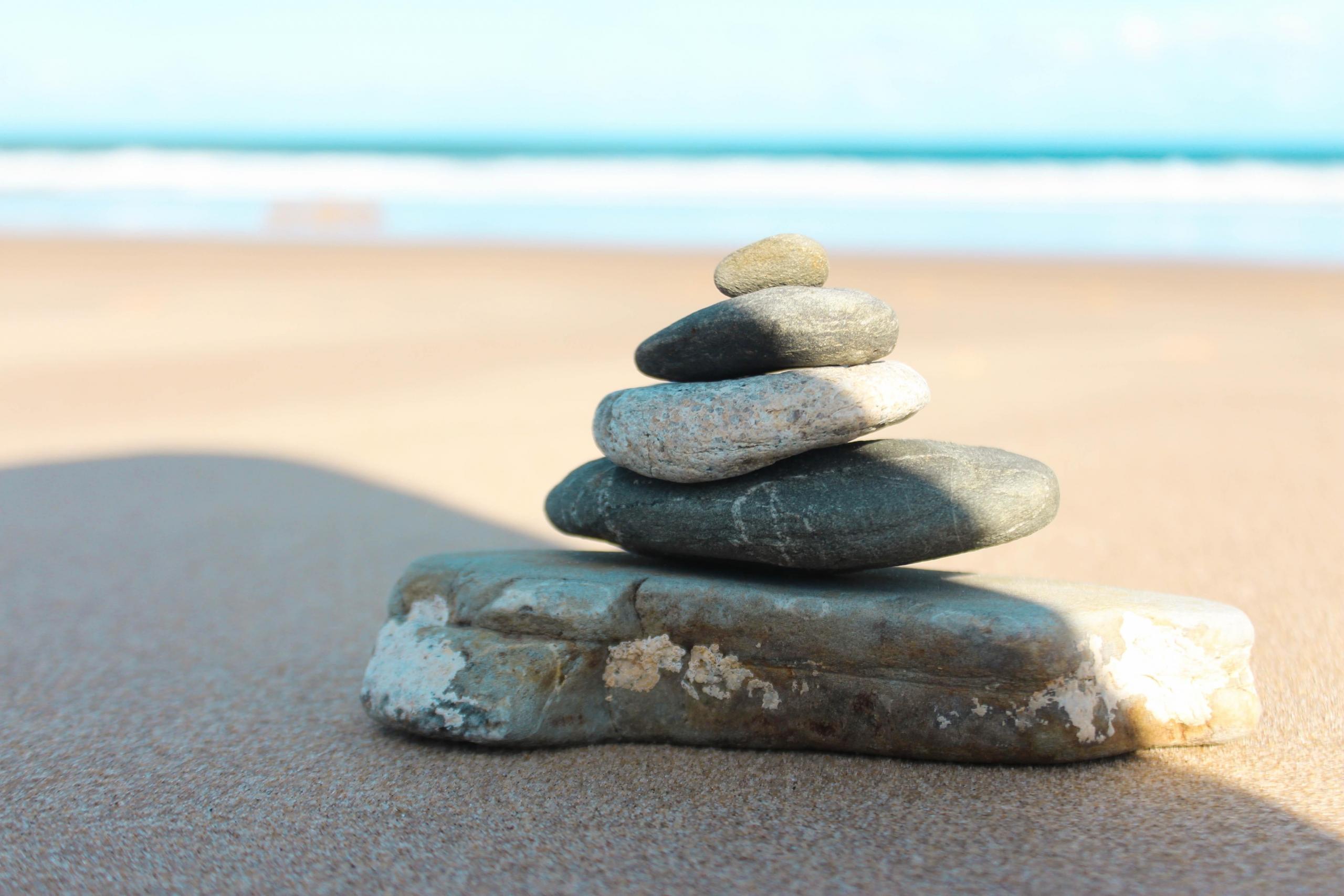 five pebbles stacked on top of each other on sandy beach