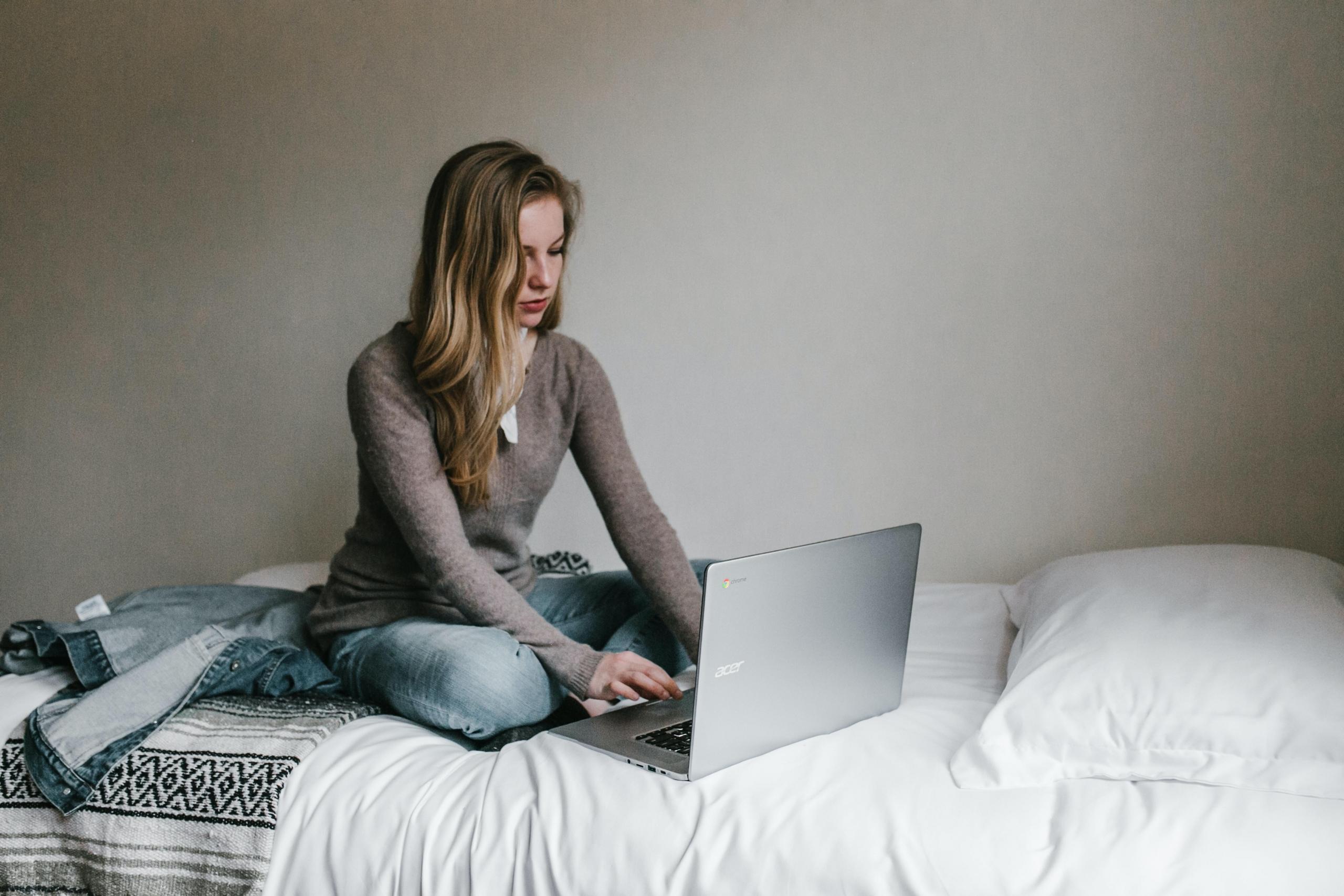 student using laptop on a bed