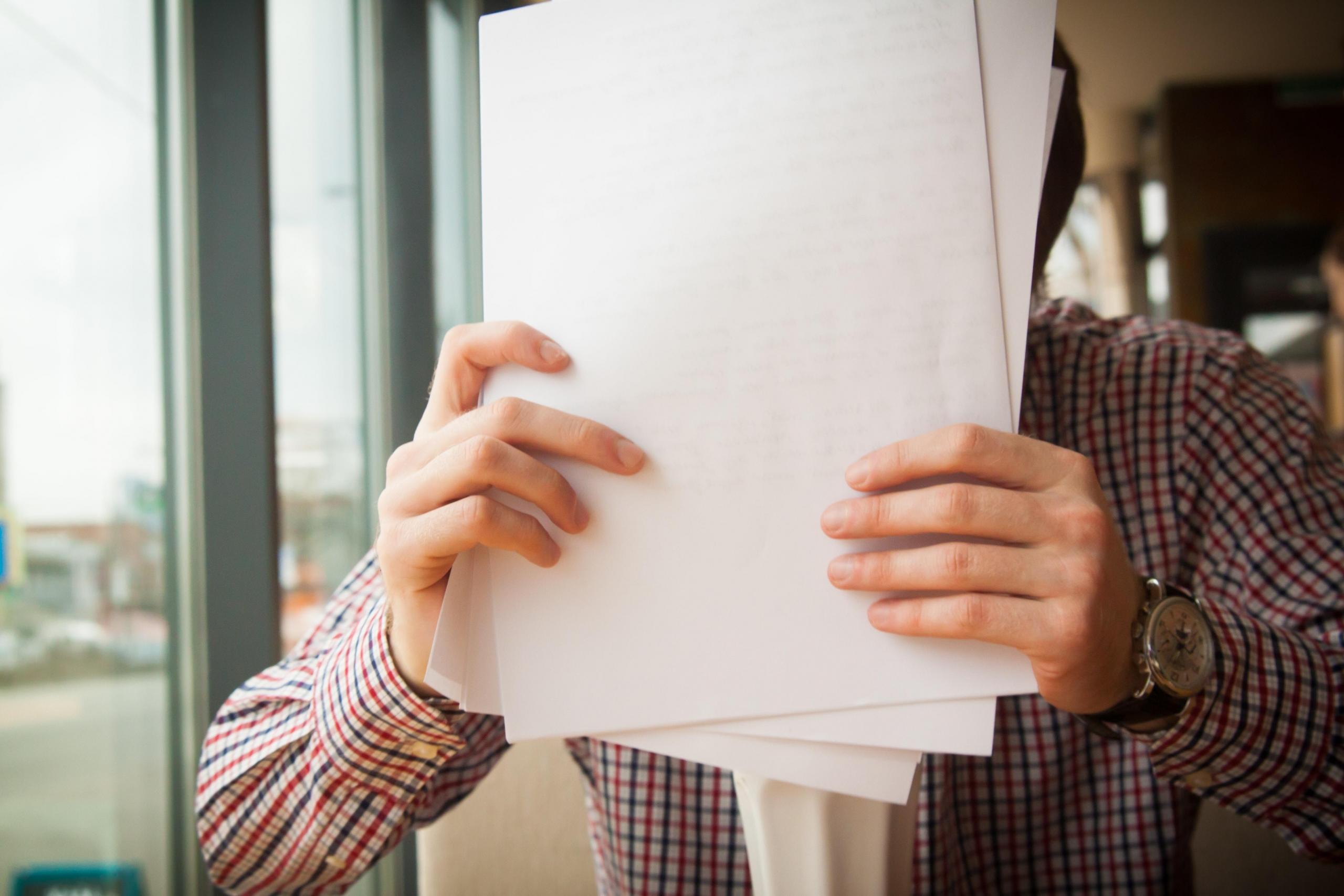 pile of paper in front of man's face