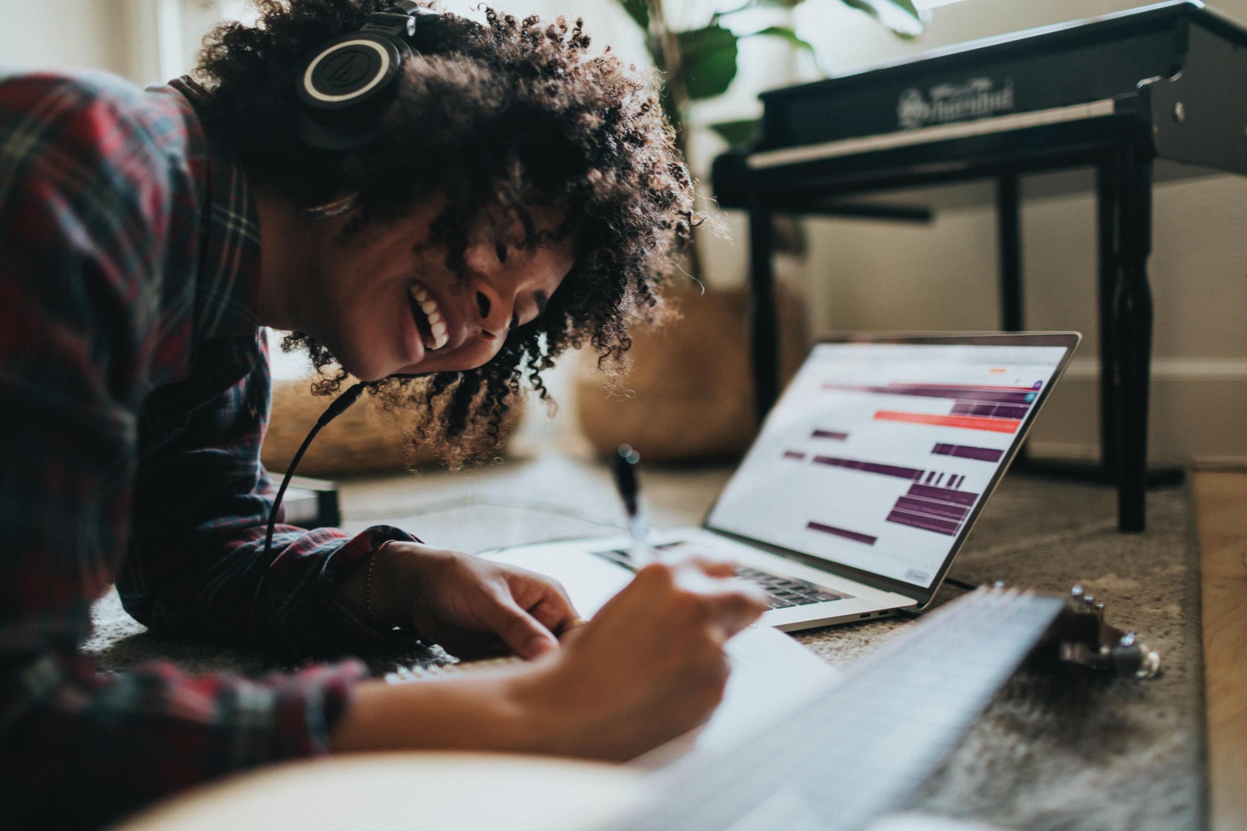 woman working on floor, wearing headphones and using laptop