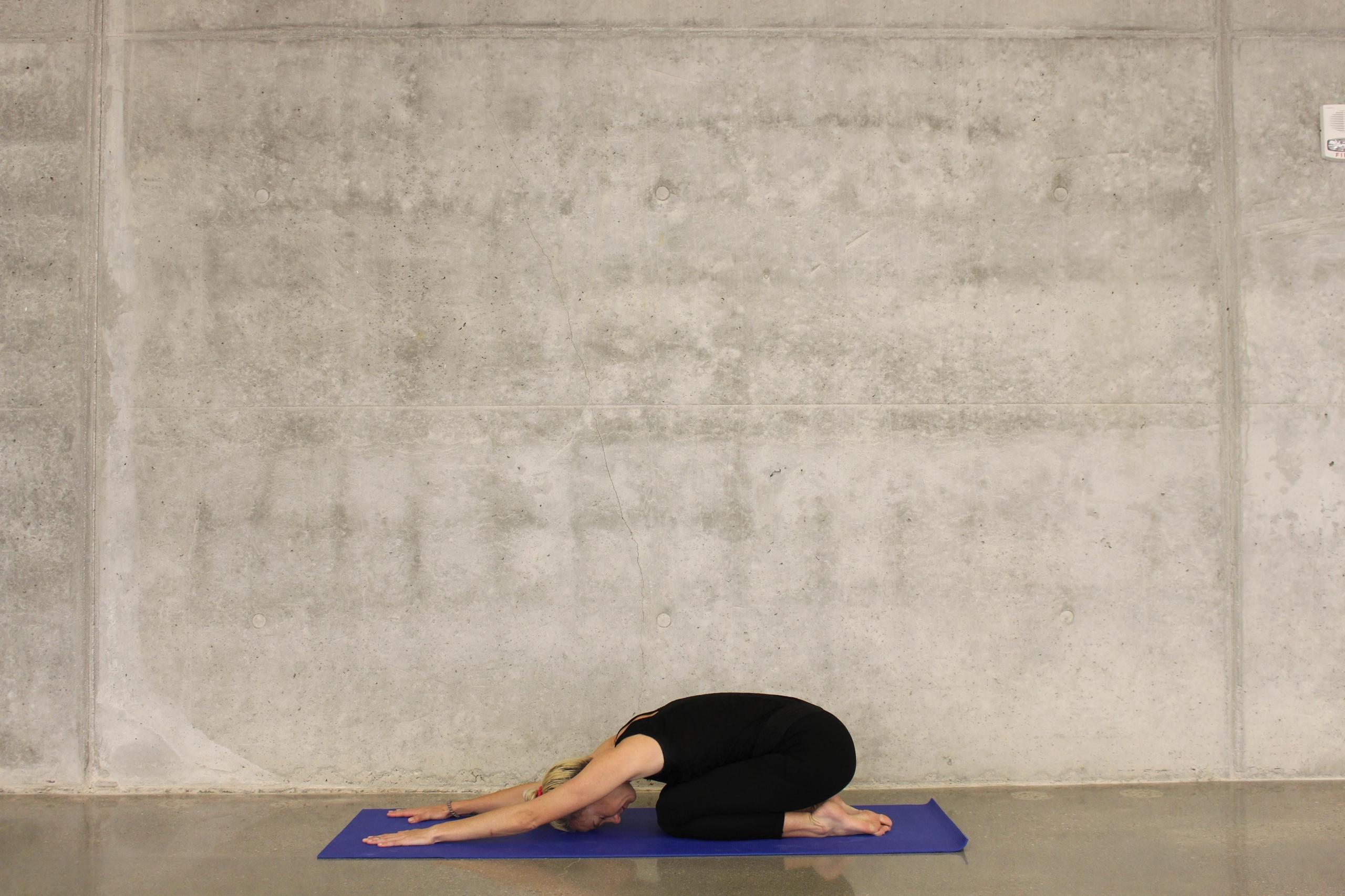 woman doing child's pose in yoga studio