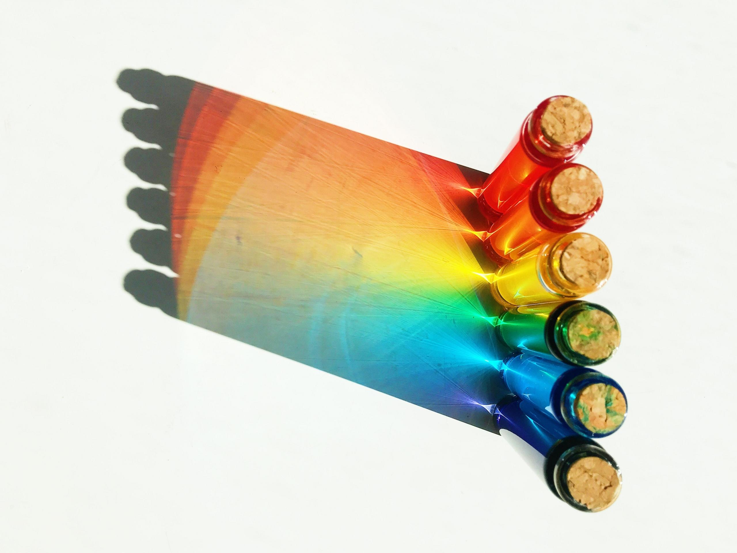 brightly coloured liquids inside test tubes creating rainbow reflection
