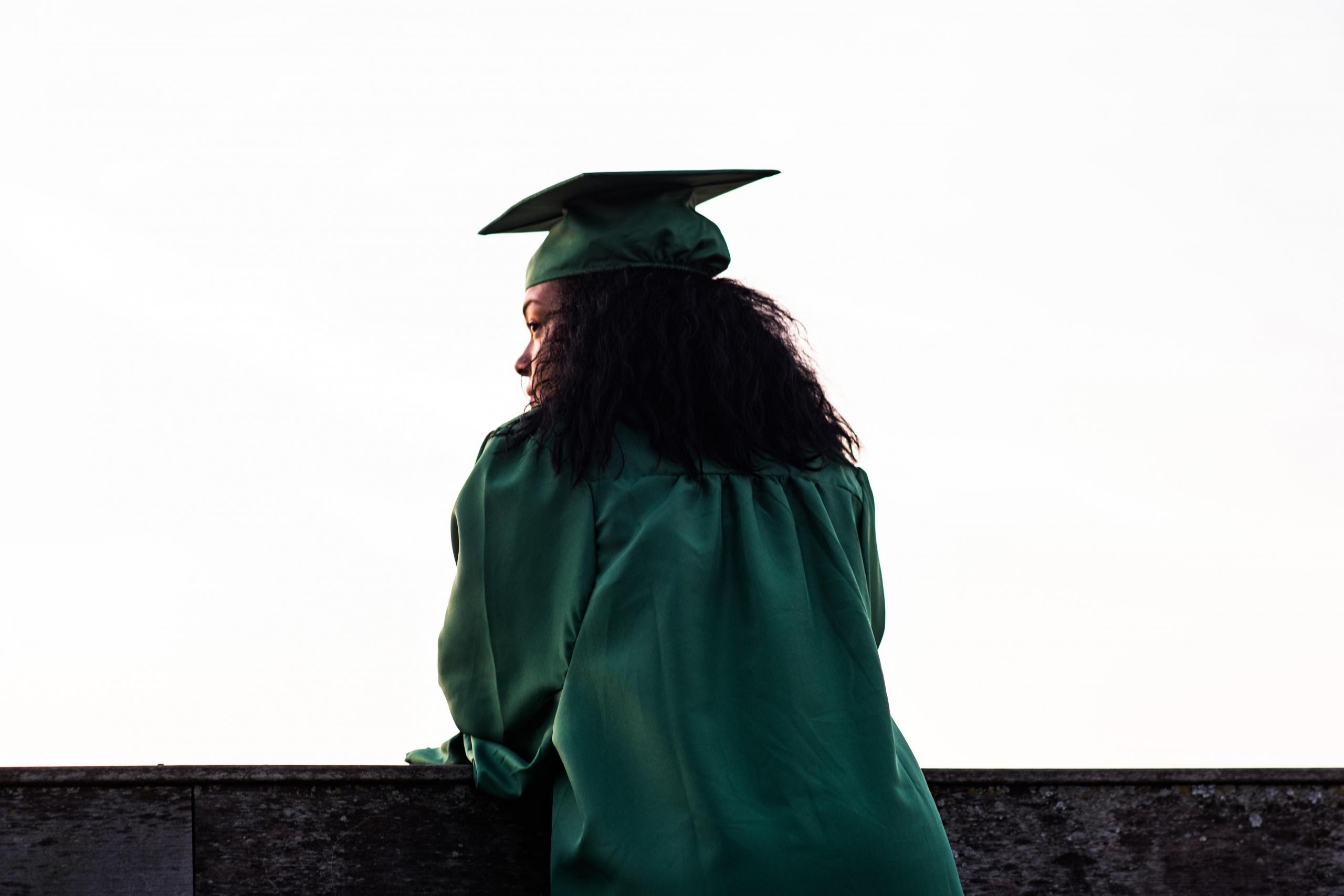 female graduate wearing green mortar board and graduation gown