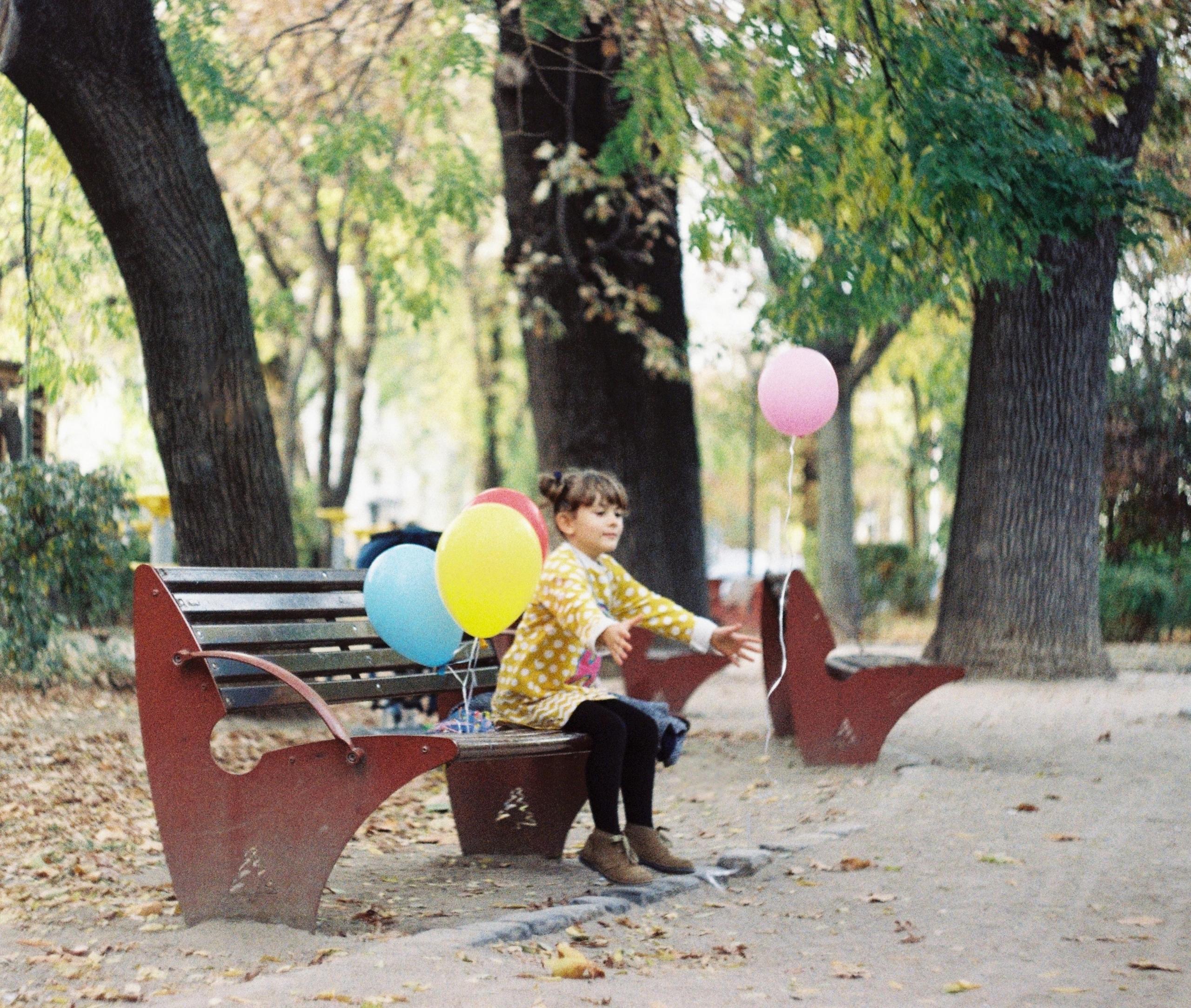 girl on bench with helium balloons