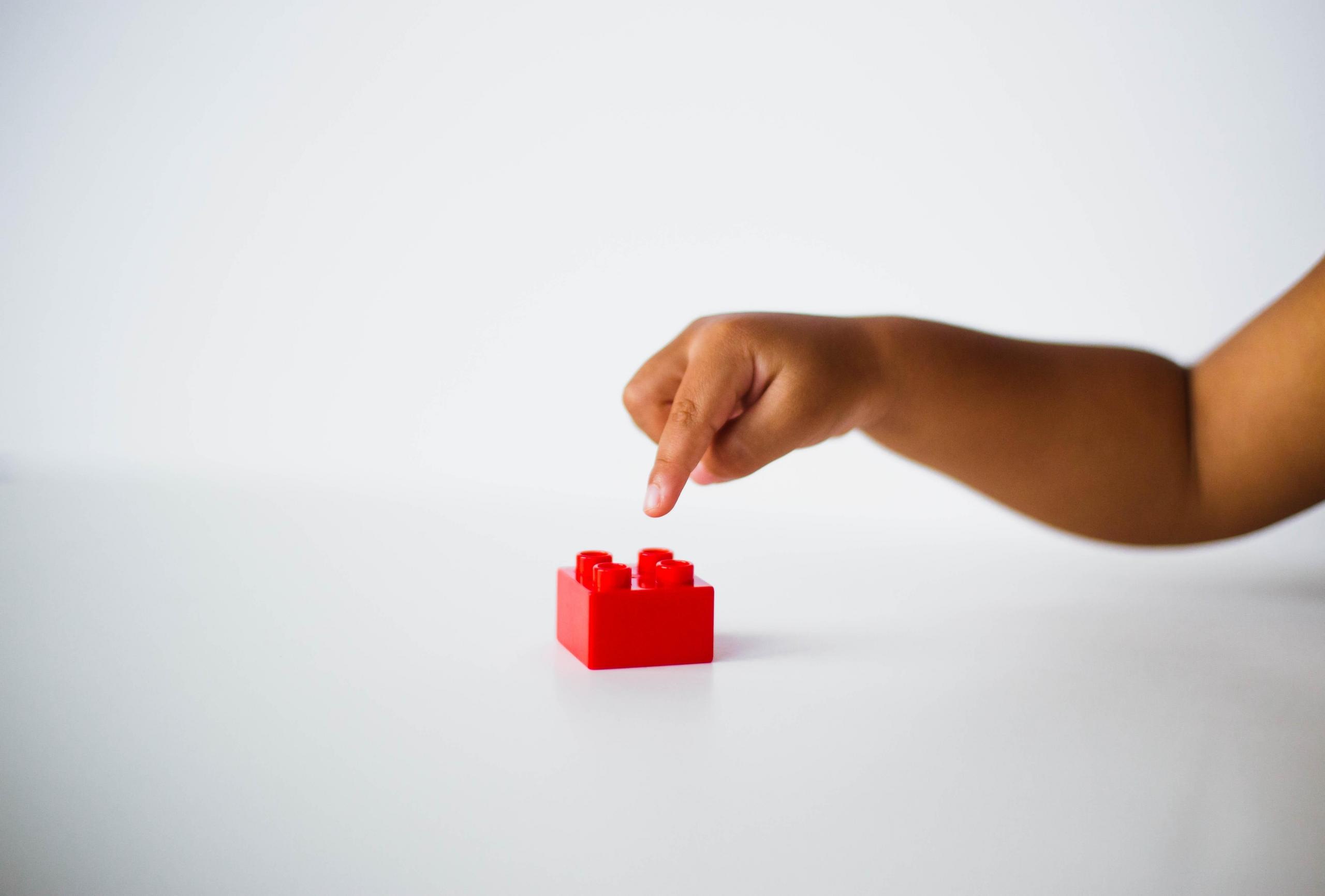 child playing with red lego brick