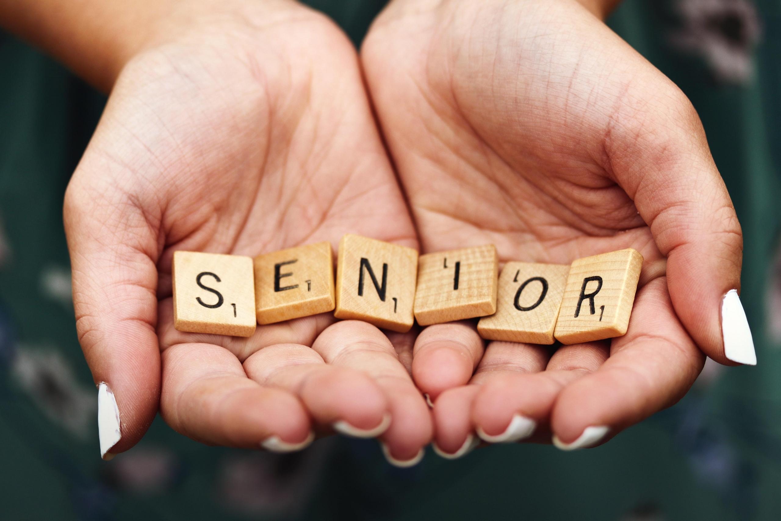 girl holding scrabble tiles which spell the word senior