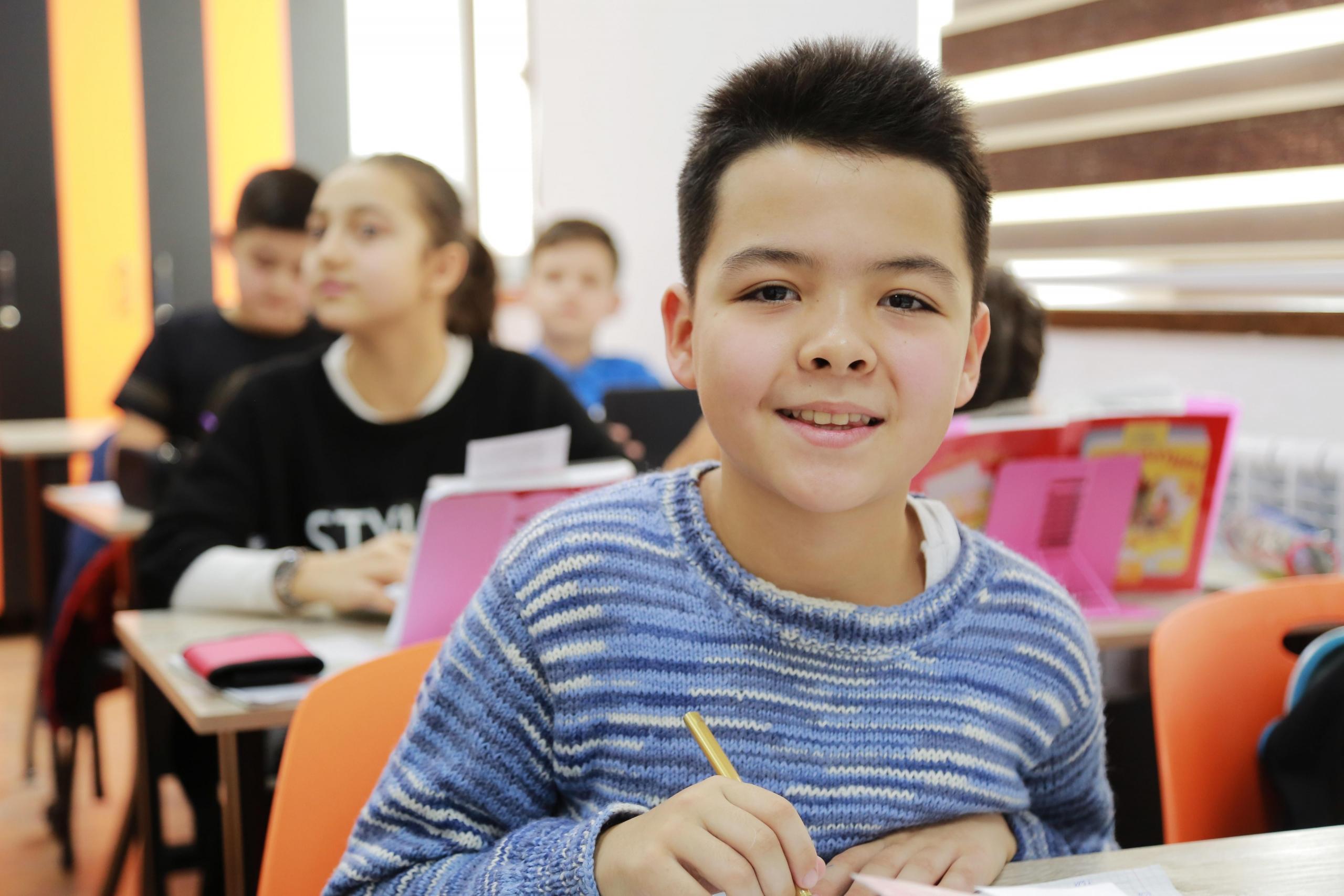 smiling schoolboy seated at desk