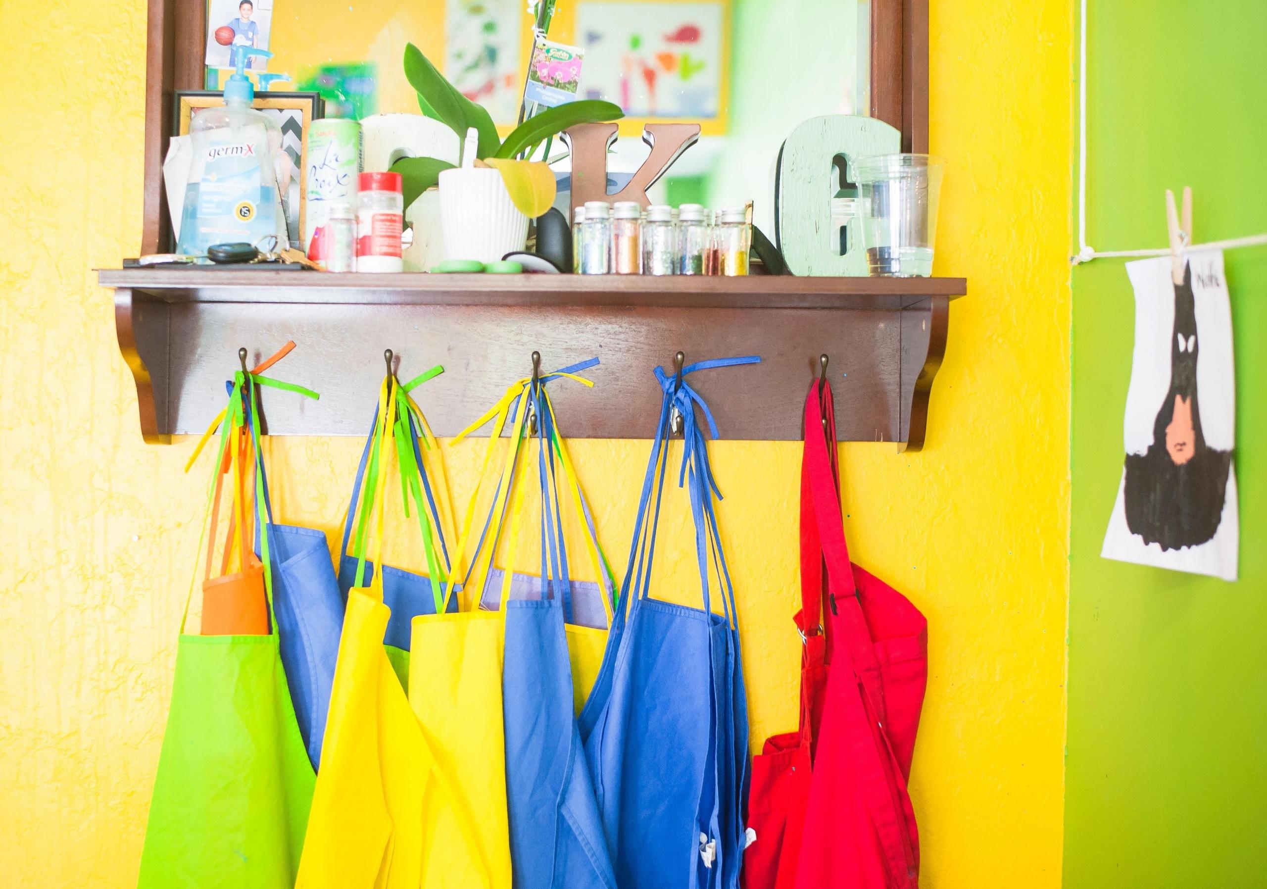 colourful children's aprons on hooks in classroom