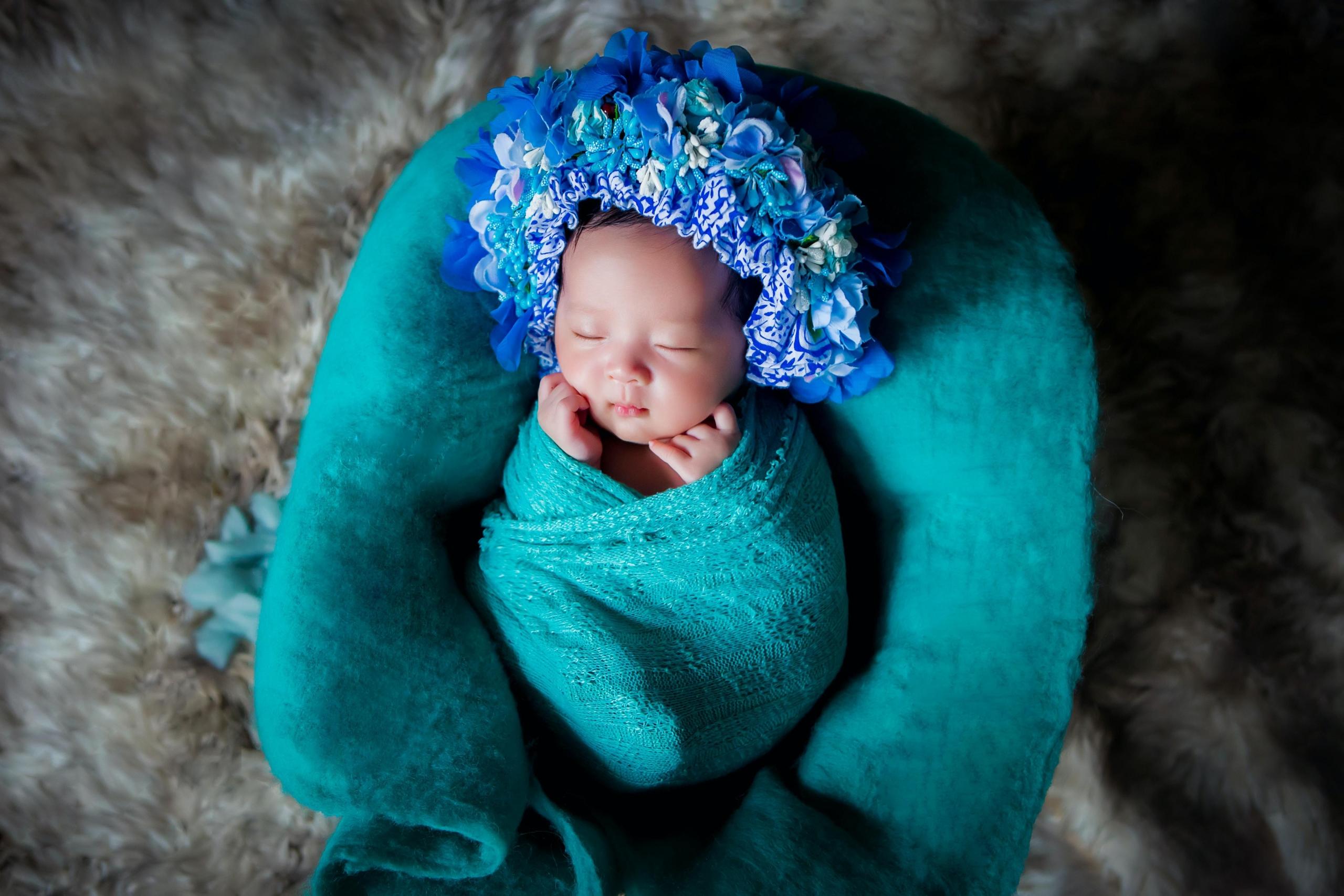 baby swaddled and wearing flower crown
