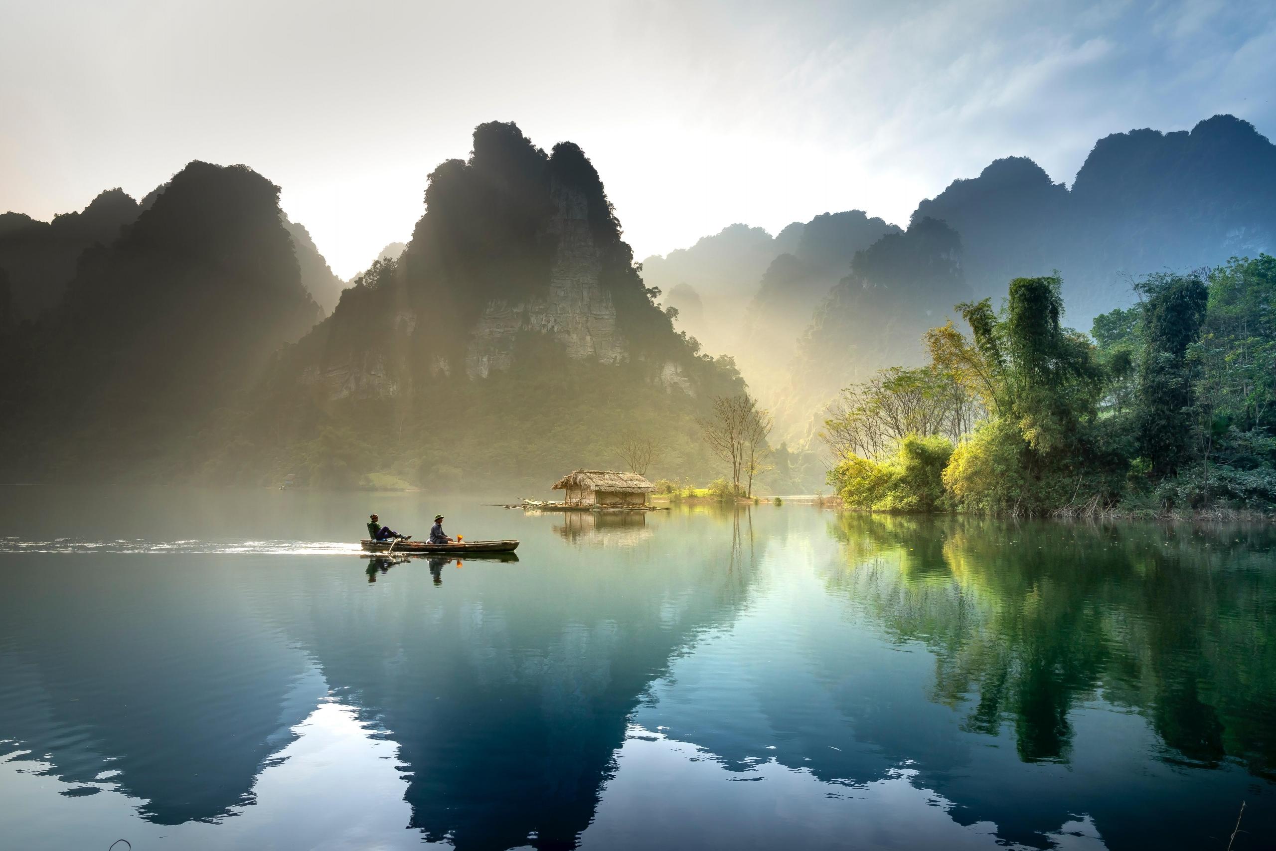 people in boat on lake, surrounded by mountains