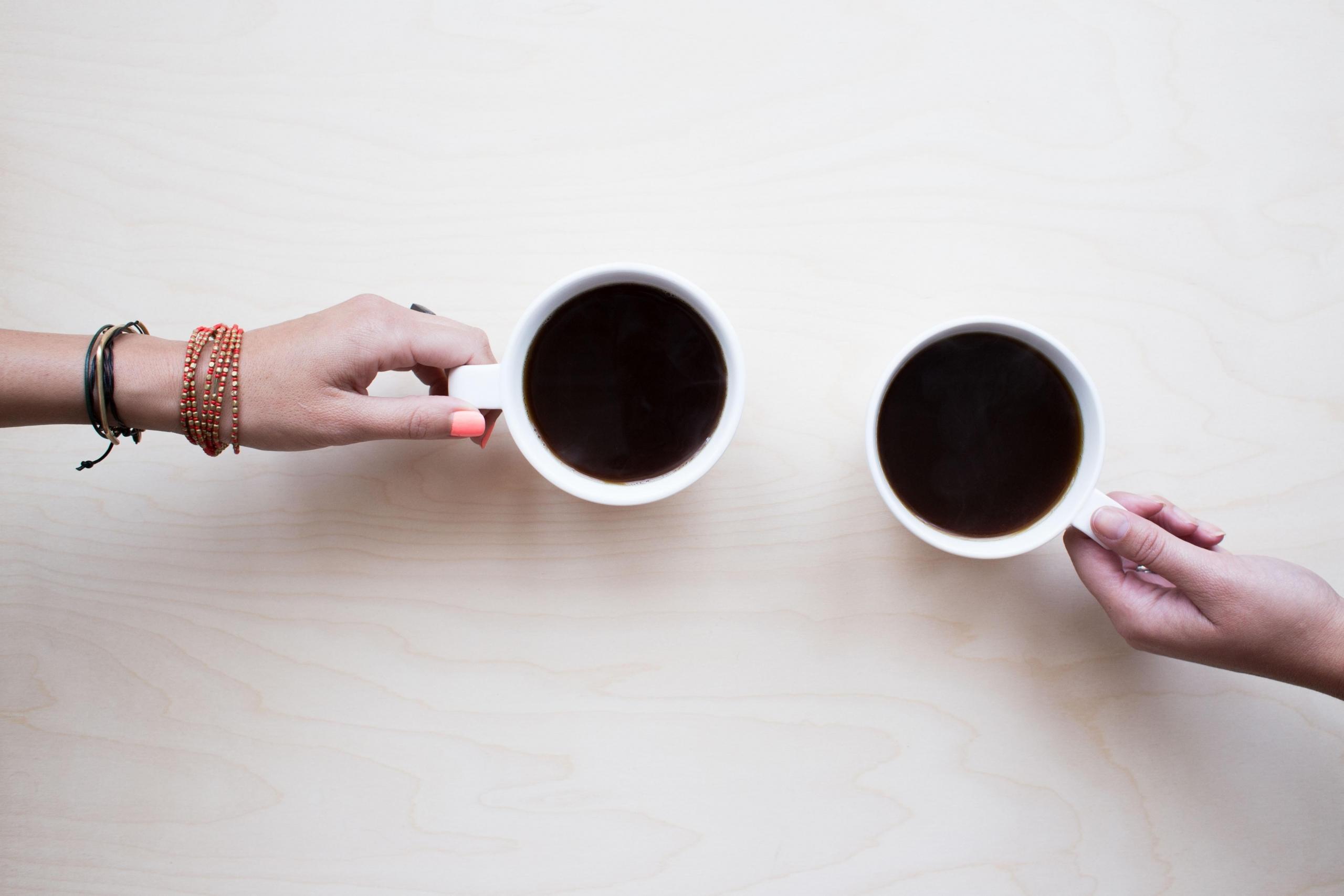 two people holding cups of coffee