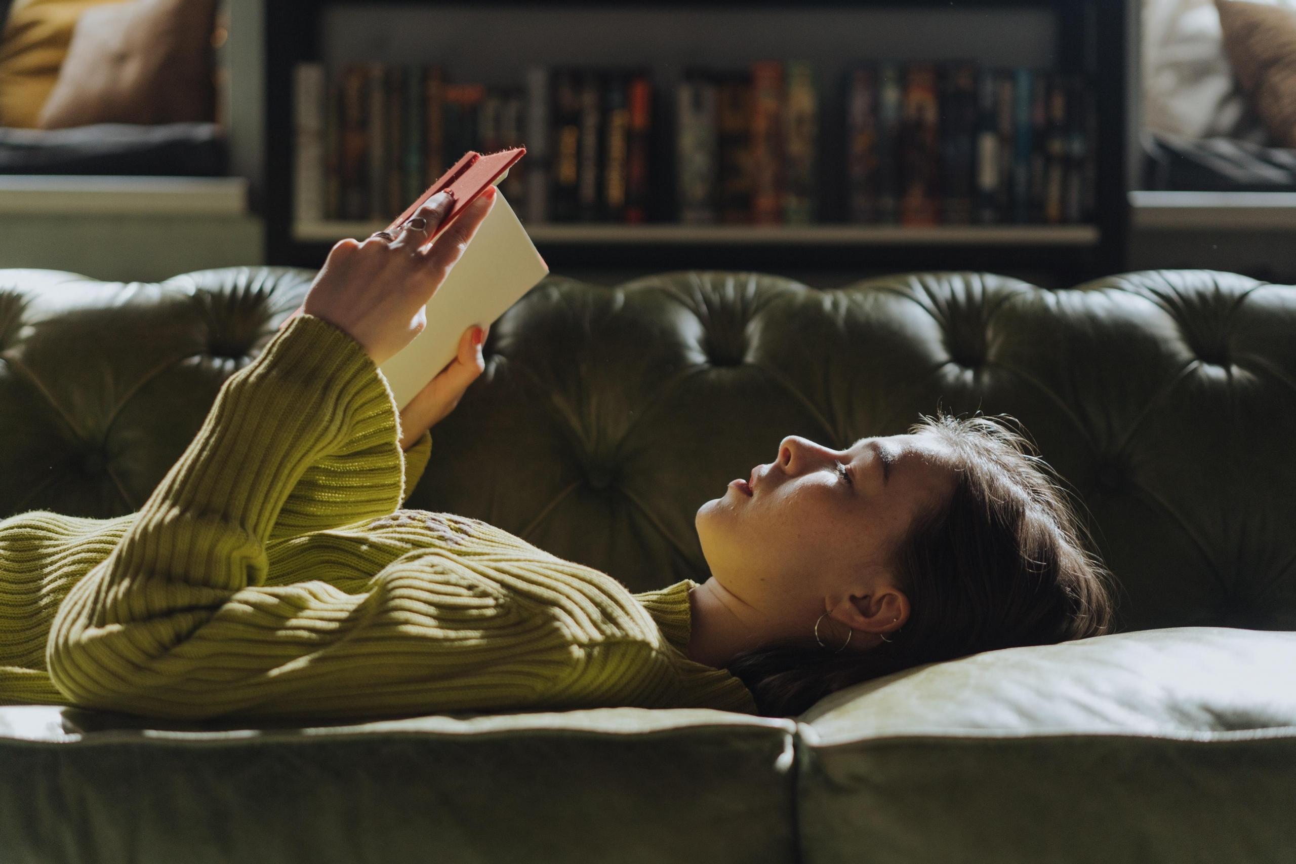 girl reading whilst lying on sofa