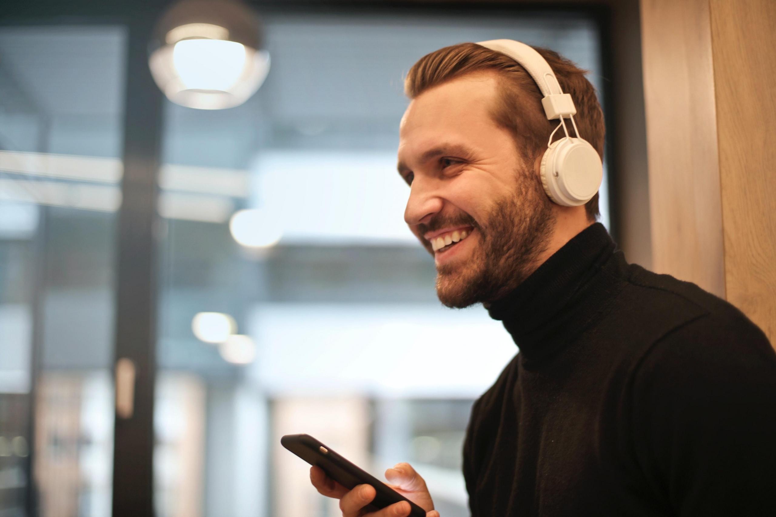 man using phone and white headphones