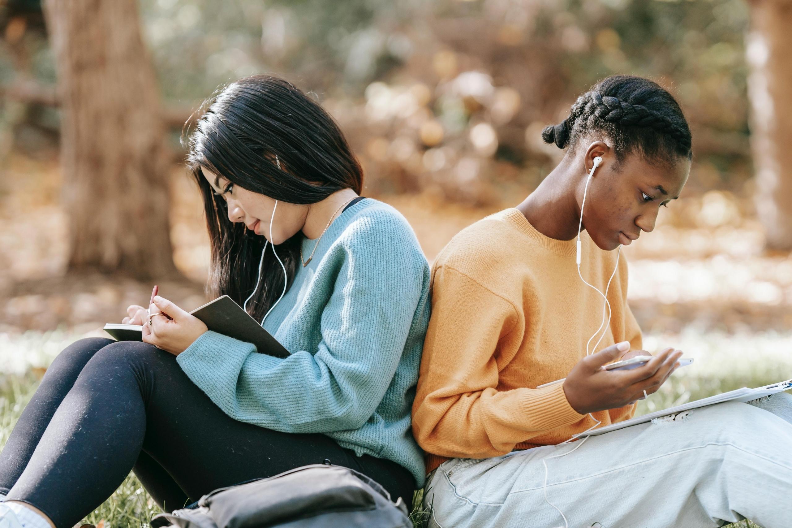 students seated back to back studying outside