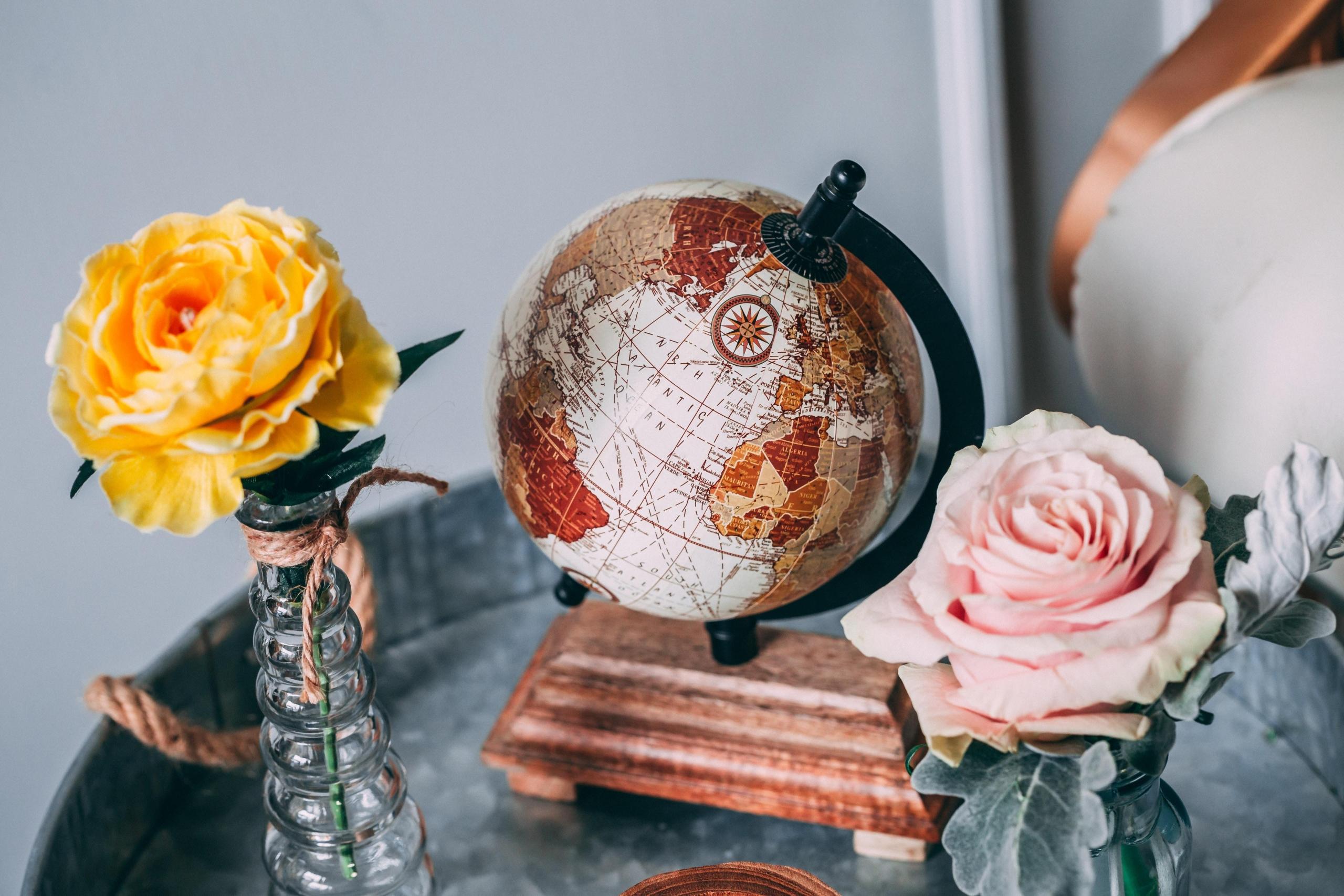earth globe on desk next to vases filled with flowers