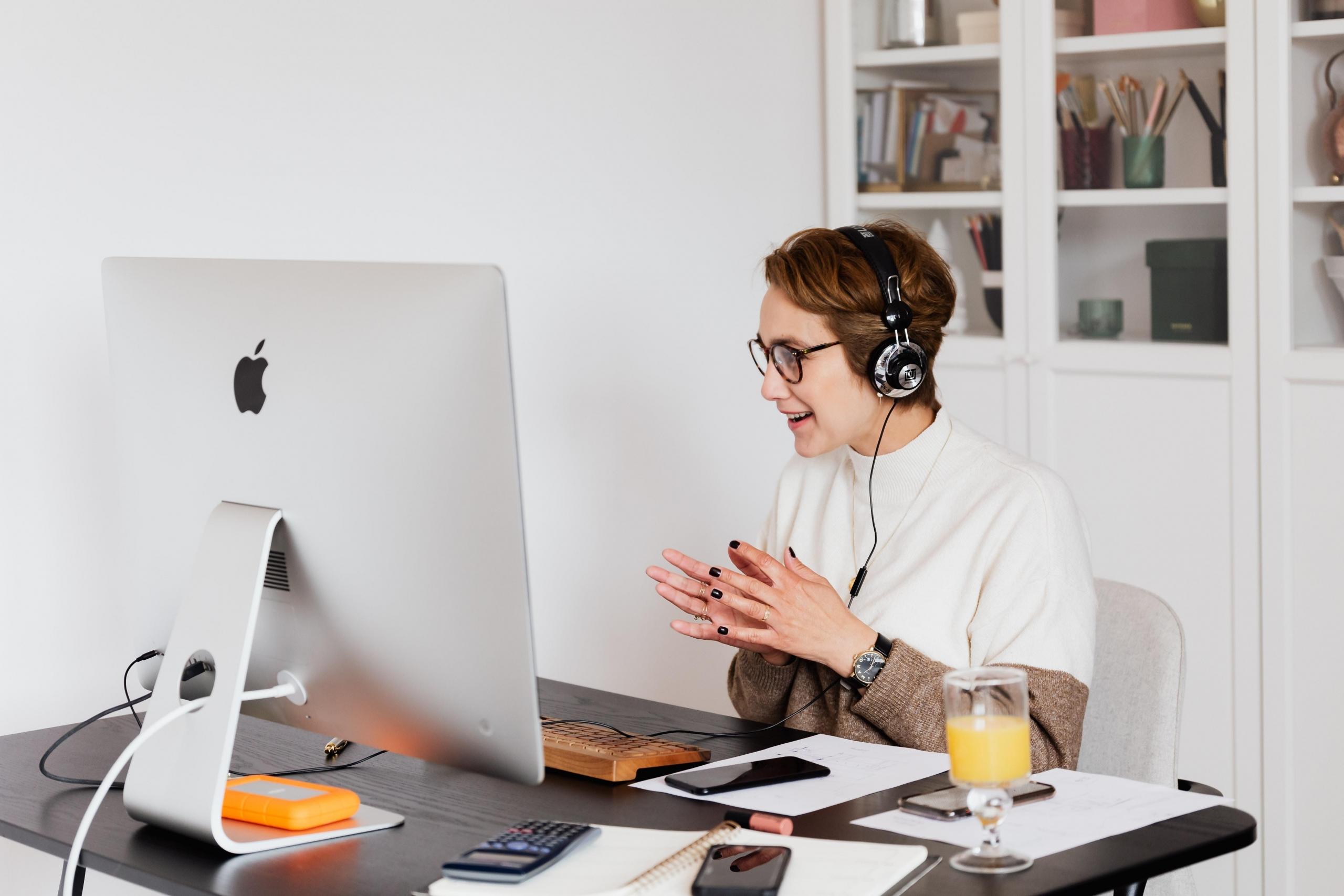 woman using headphones and desktop computer