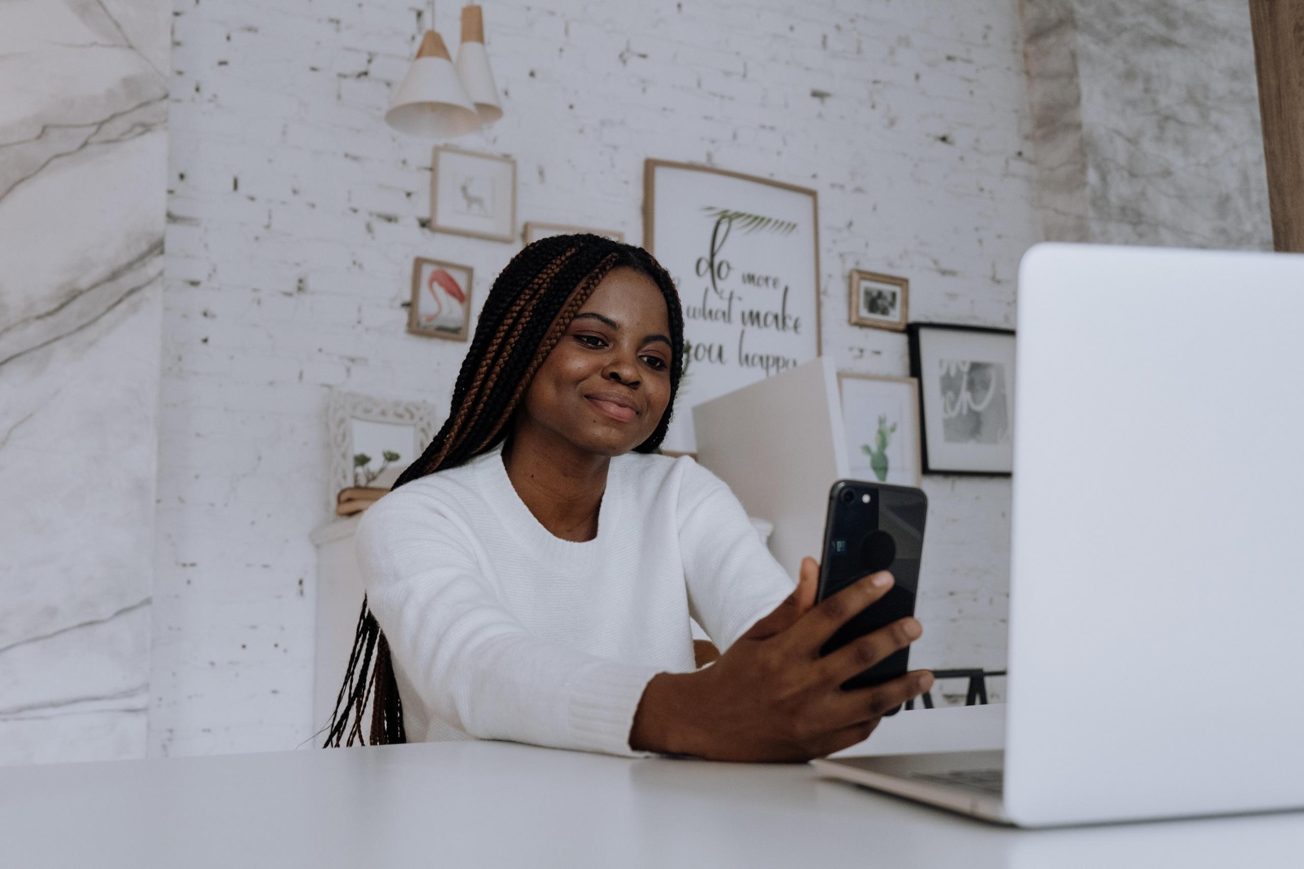 woman at desk using phone and computer