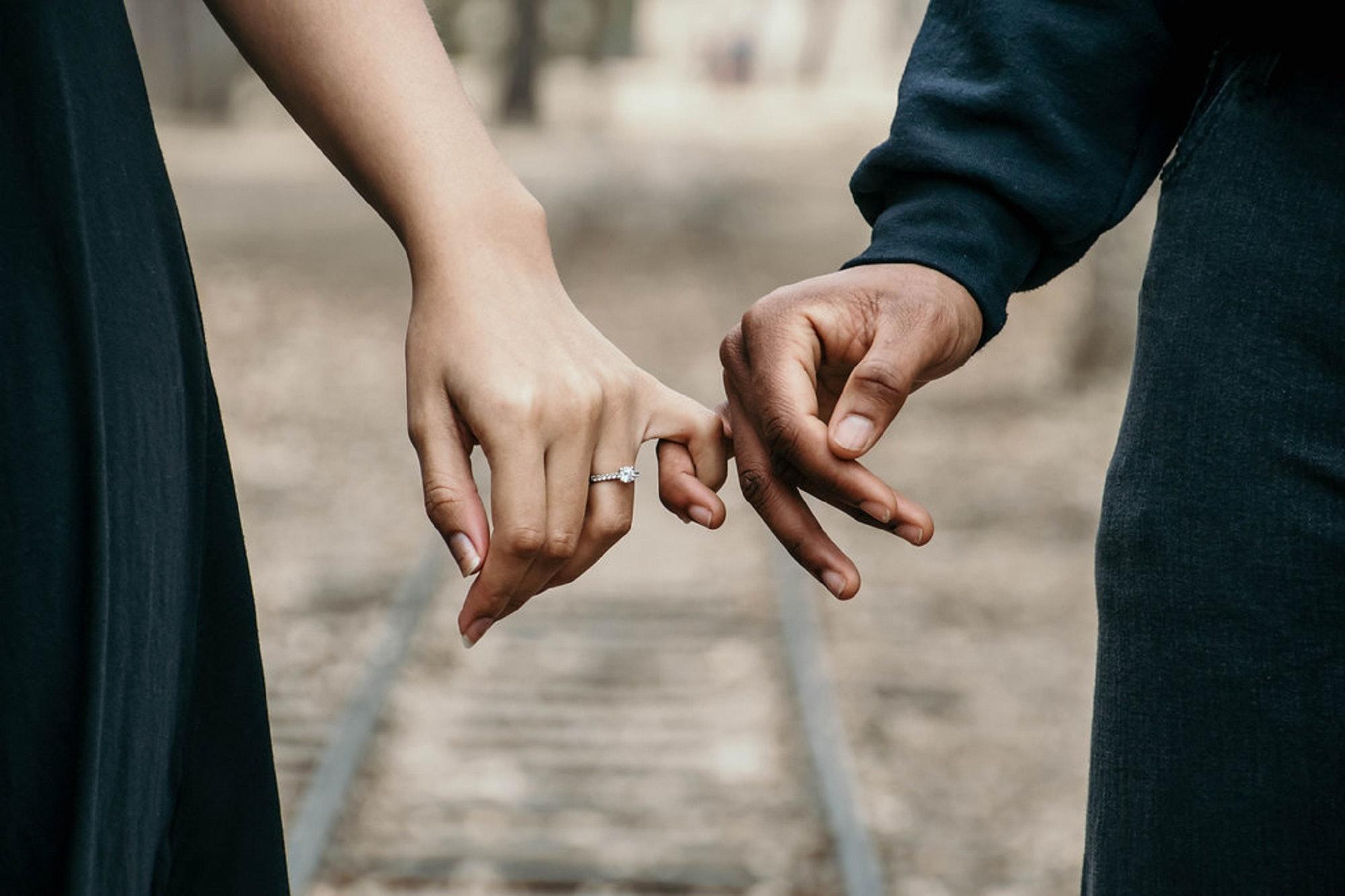 man and woman walking with pinkie fingers intertwined