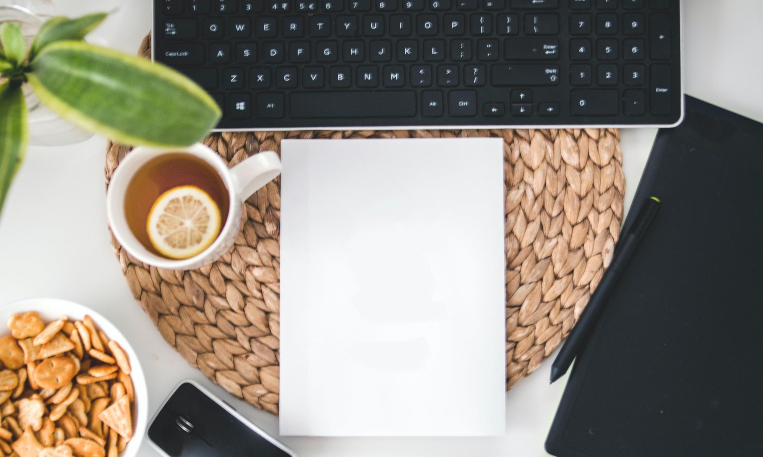 mug of lemon tea, stationery and laptop on desk