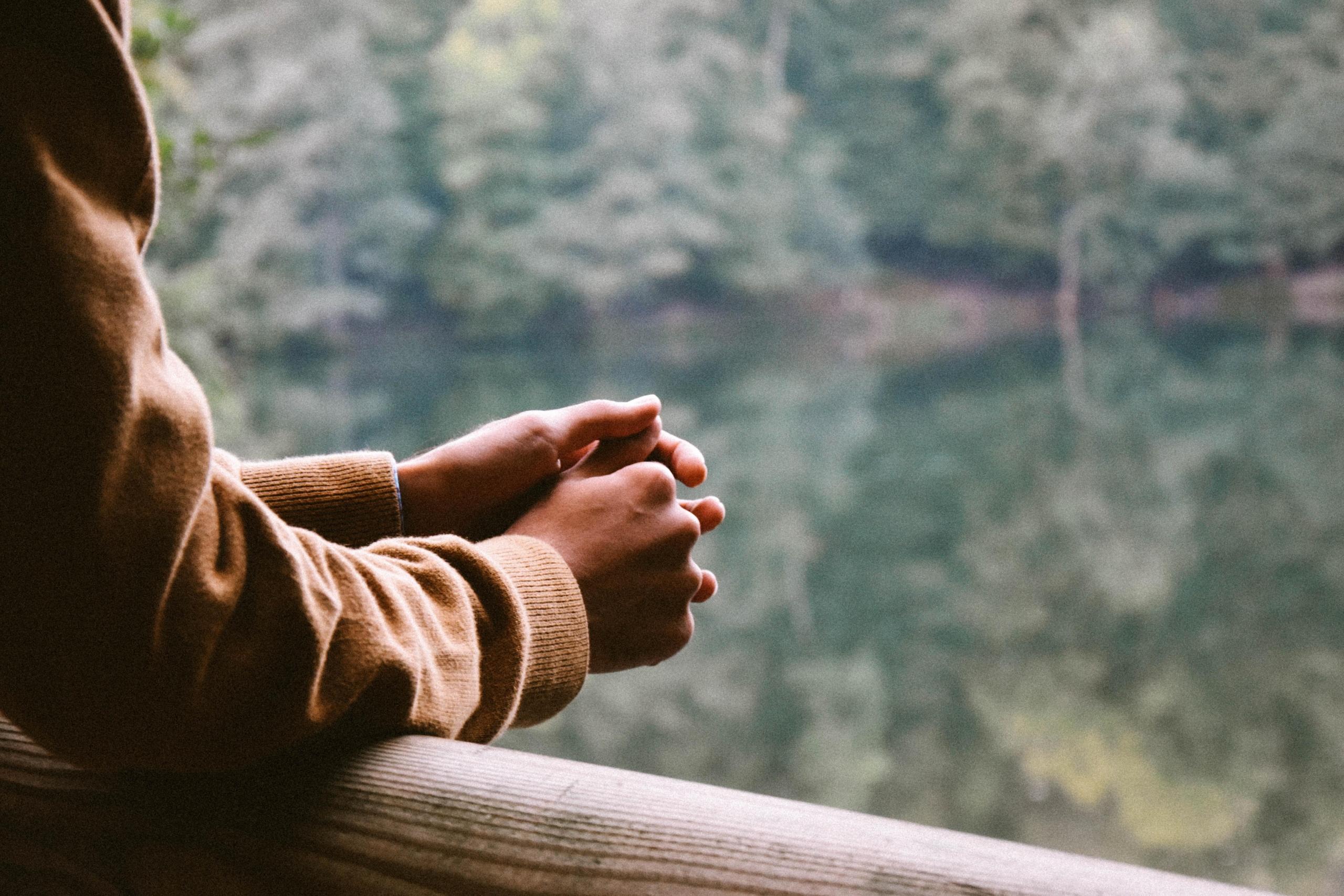 person dangling hands over outdoor railing