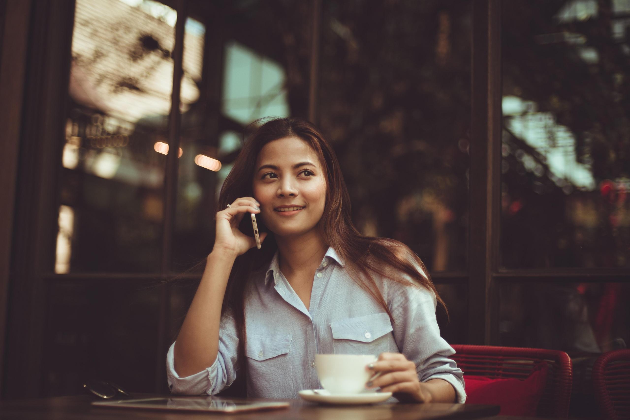 woman seated at cafe talking on smartphone