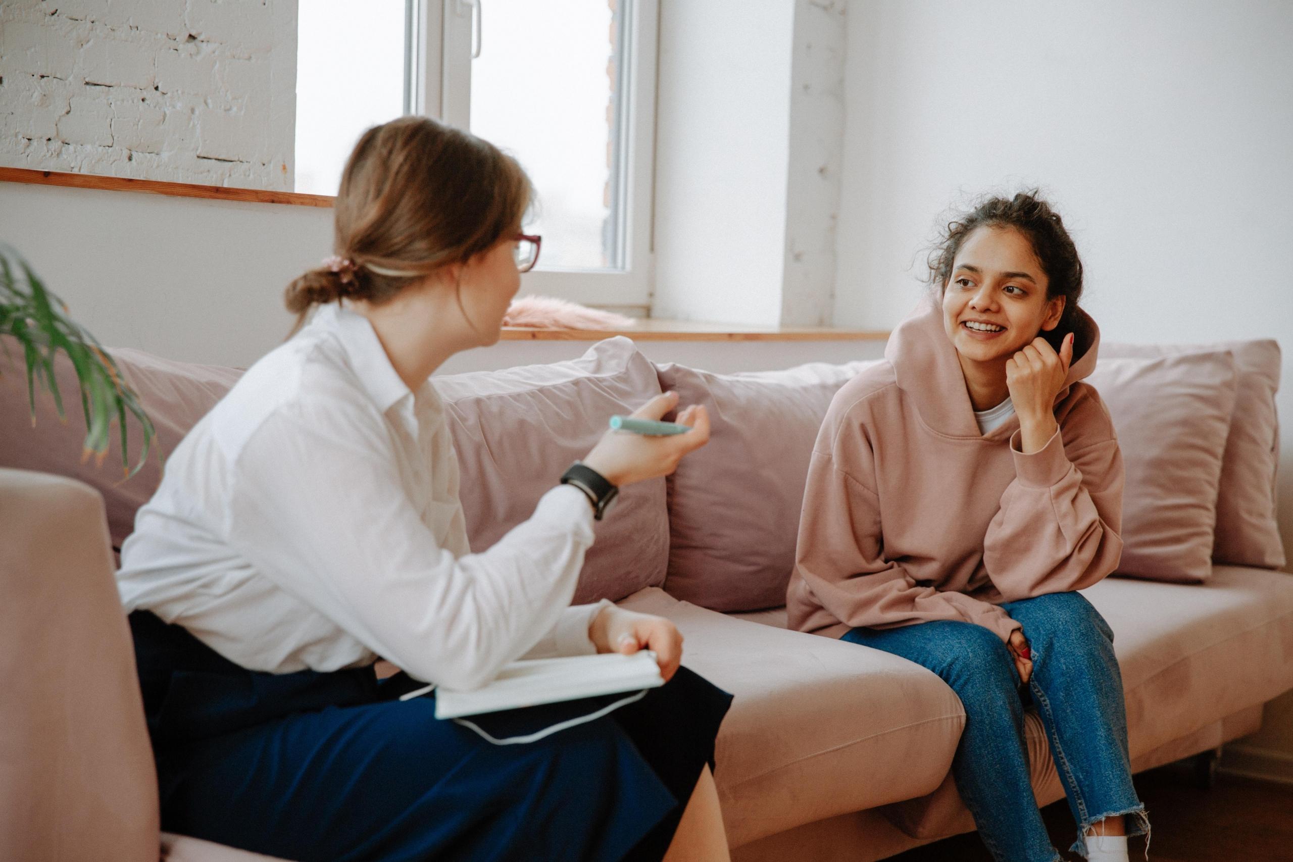 two women having a conversation on a couch