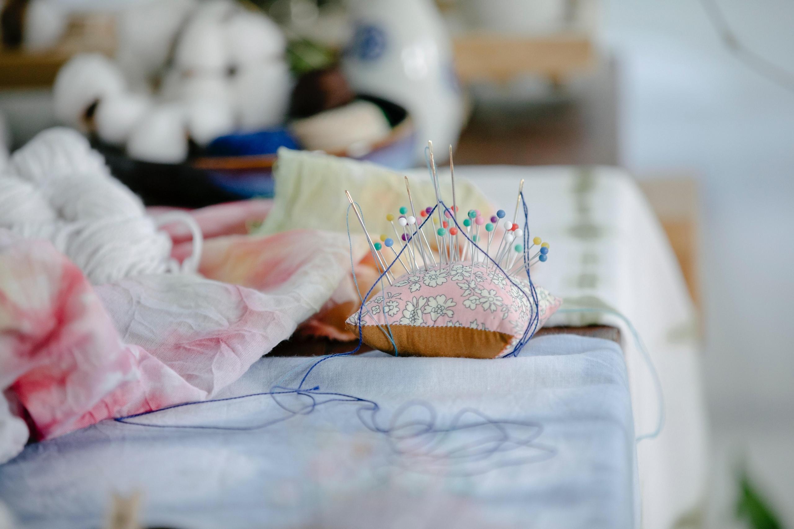 fabric, pins and pincushion on table