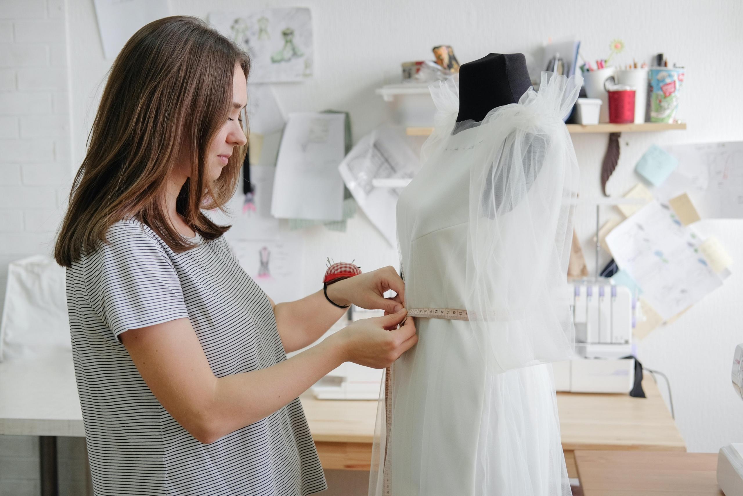 woman measuring dress on dress form