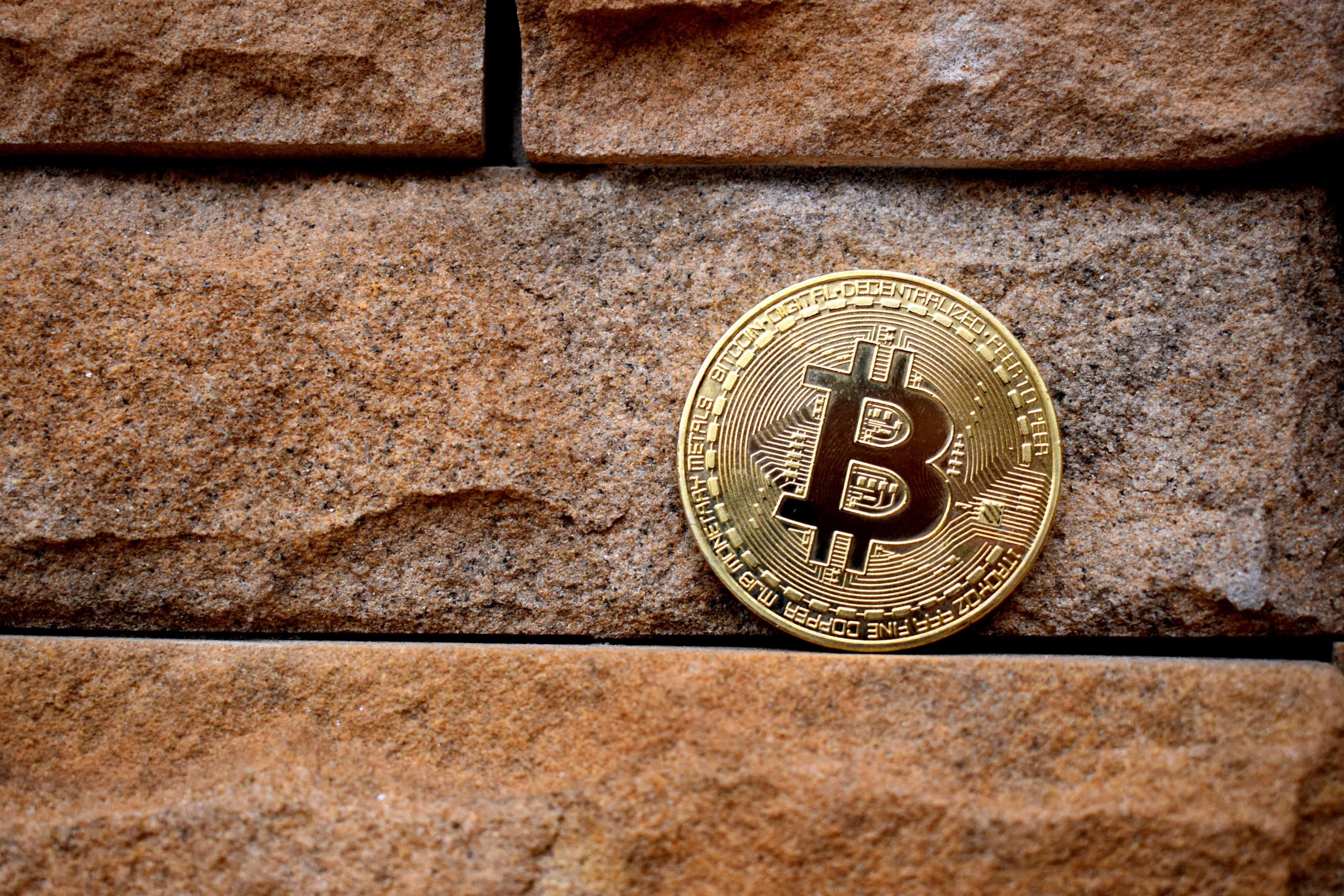 Bitcoin coin placed on brown brick wall