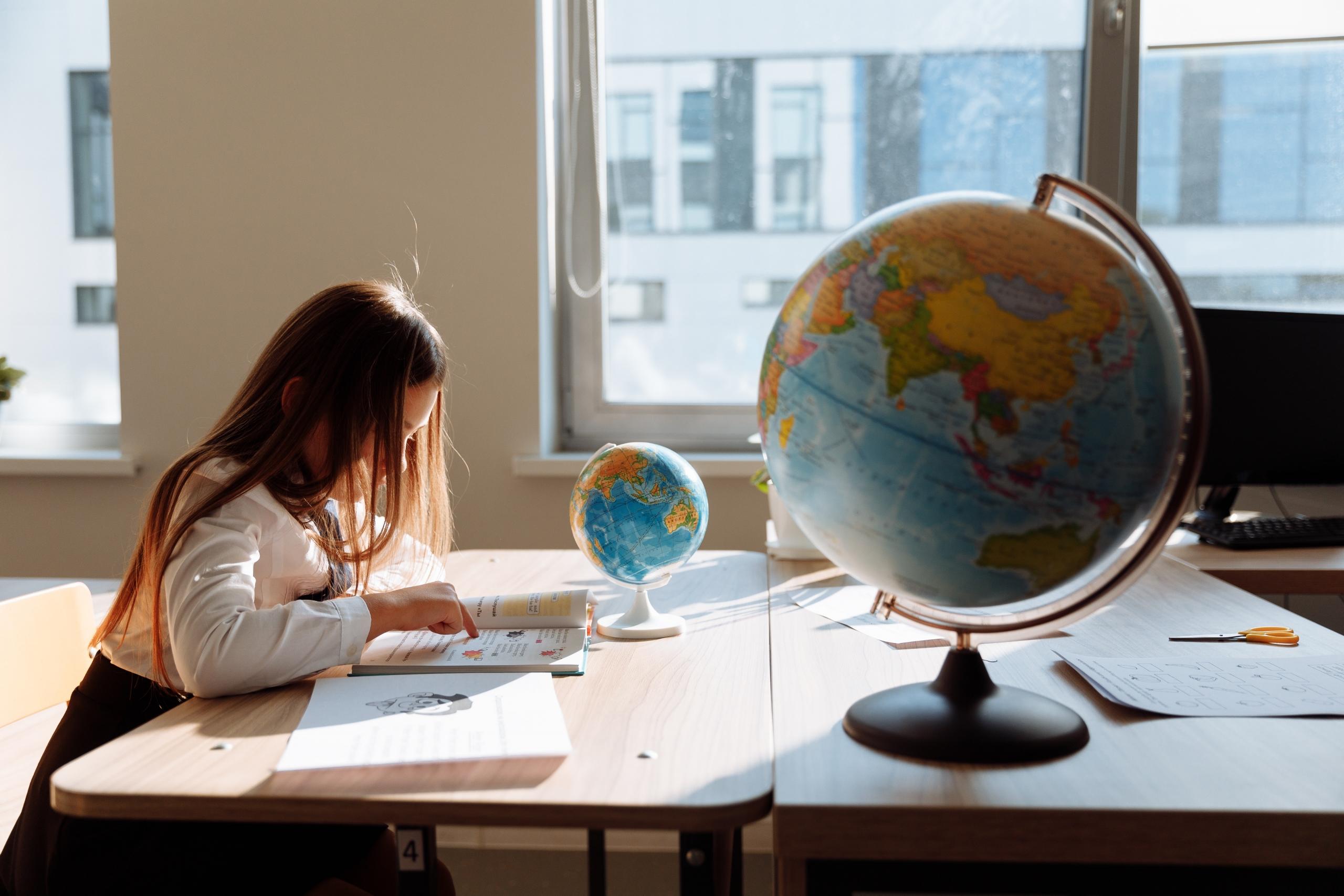 girl doing homework with two world globes on desk