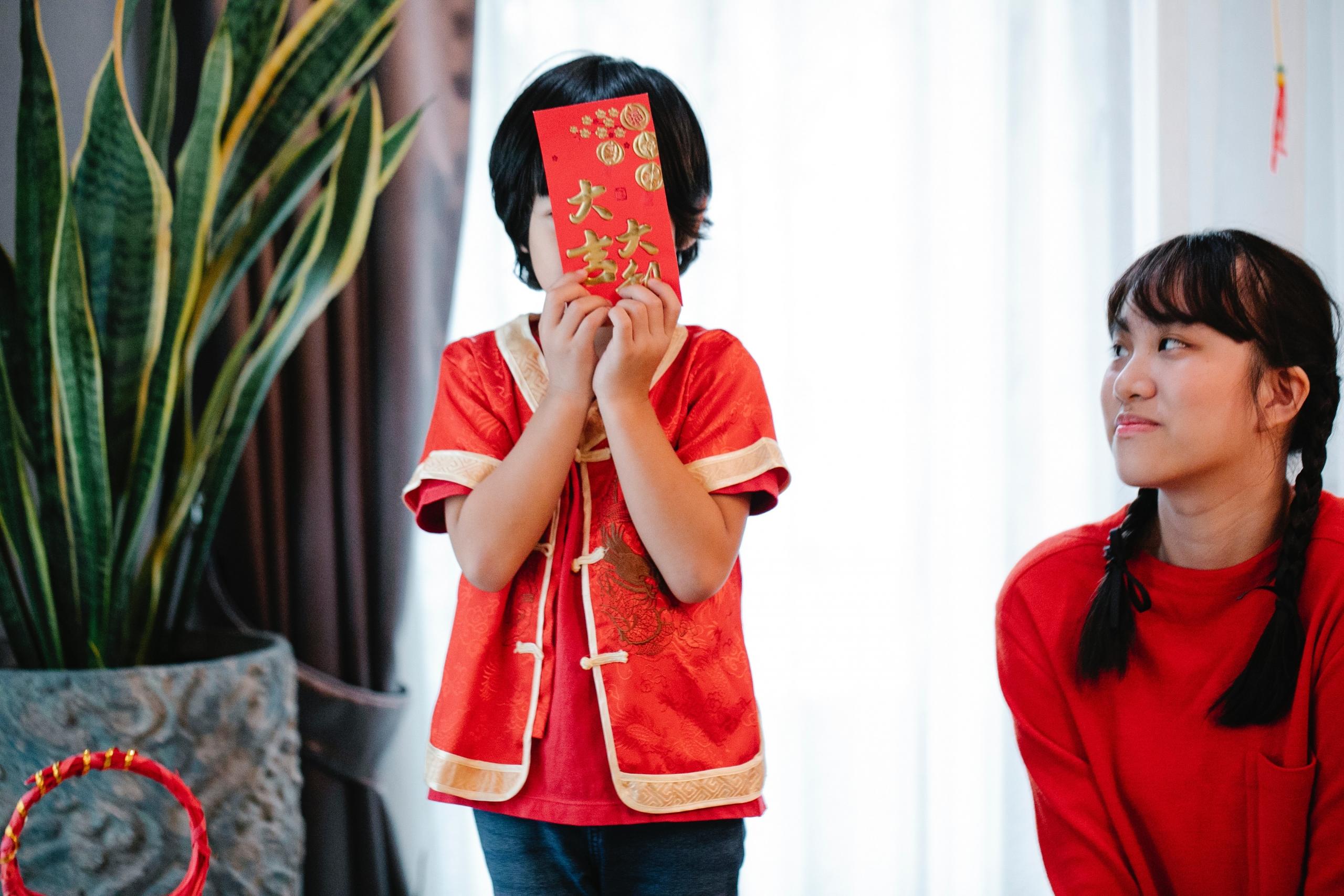 boy holding read Chinese New Year card infront of face