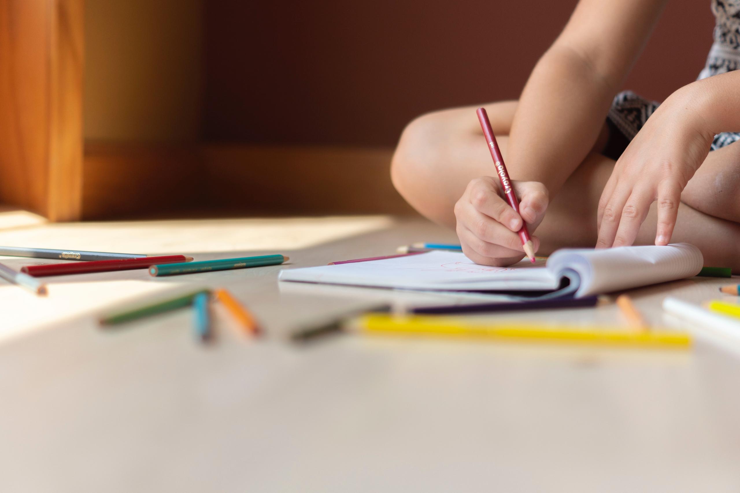 Child using coloured pencils in exercise book