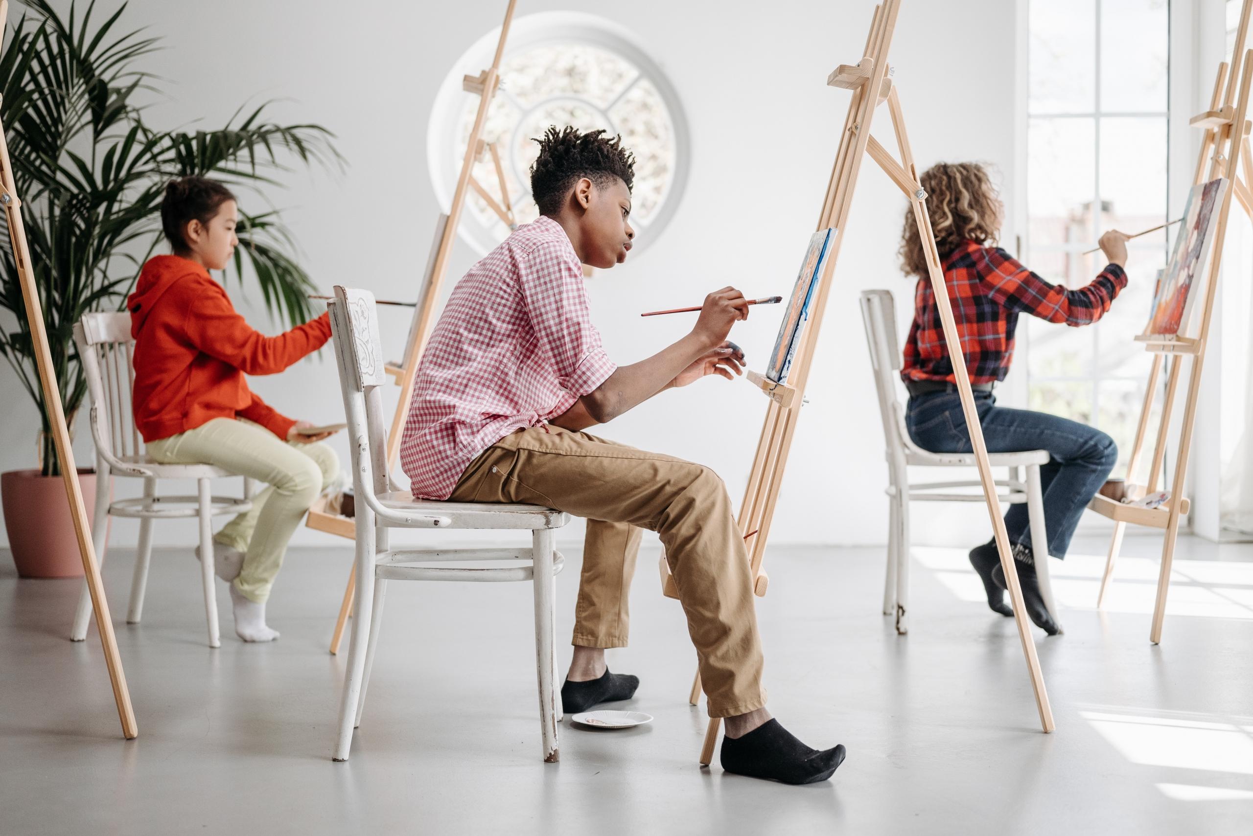 children learning to paint in group art lesson