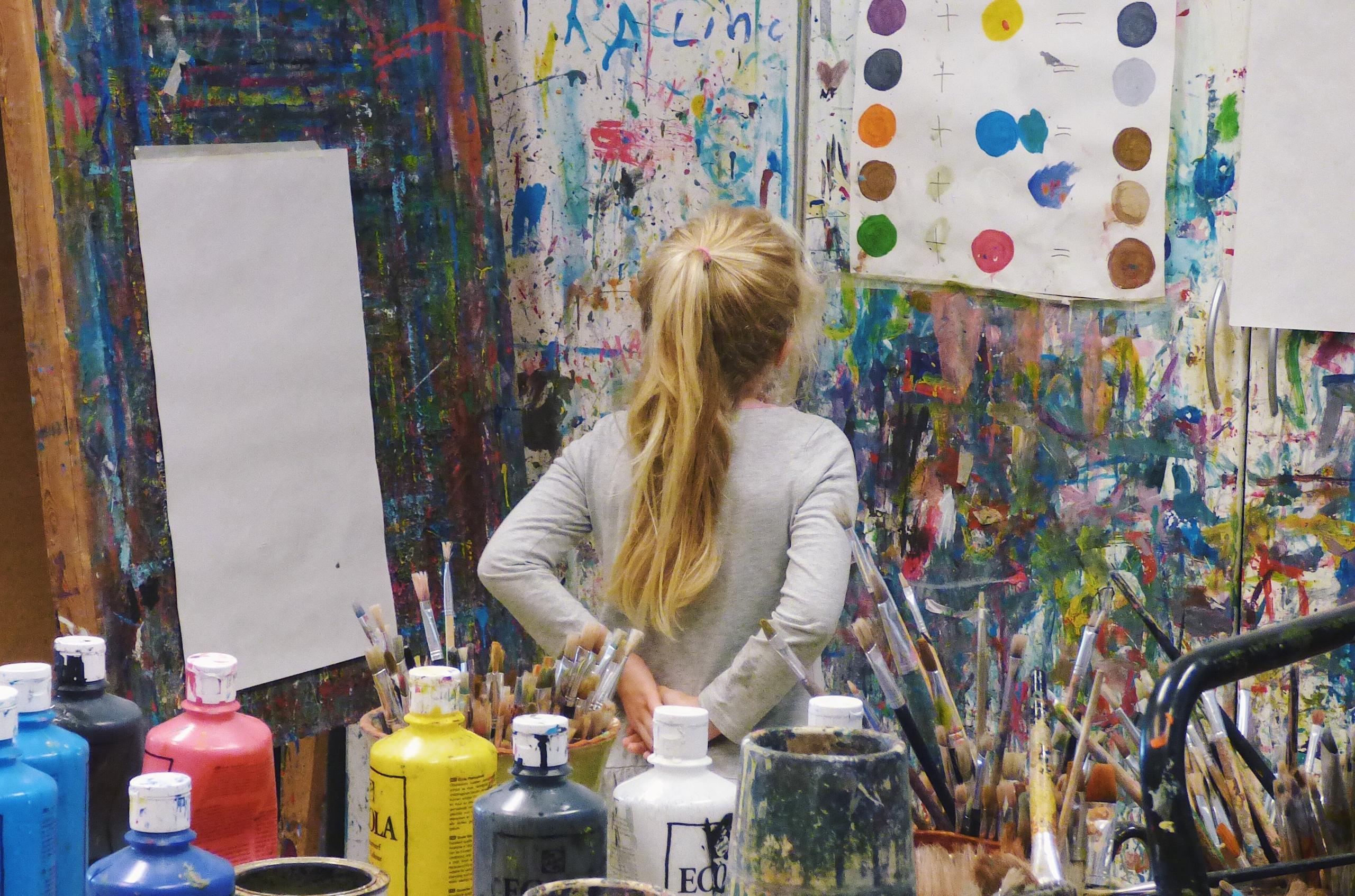 little girl looking at paint colours on paint splattered wall