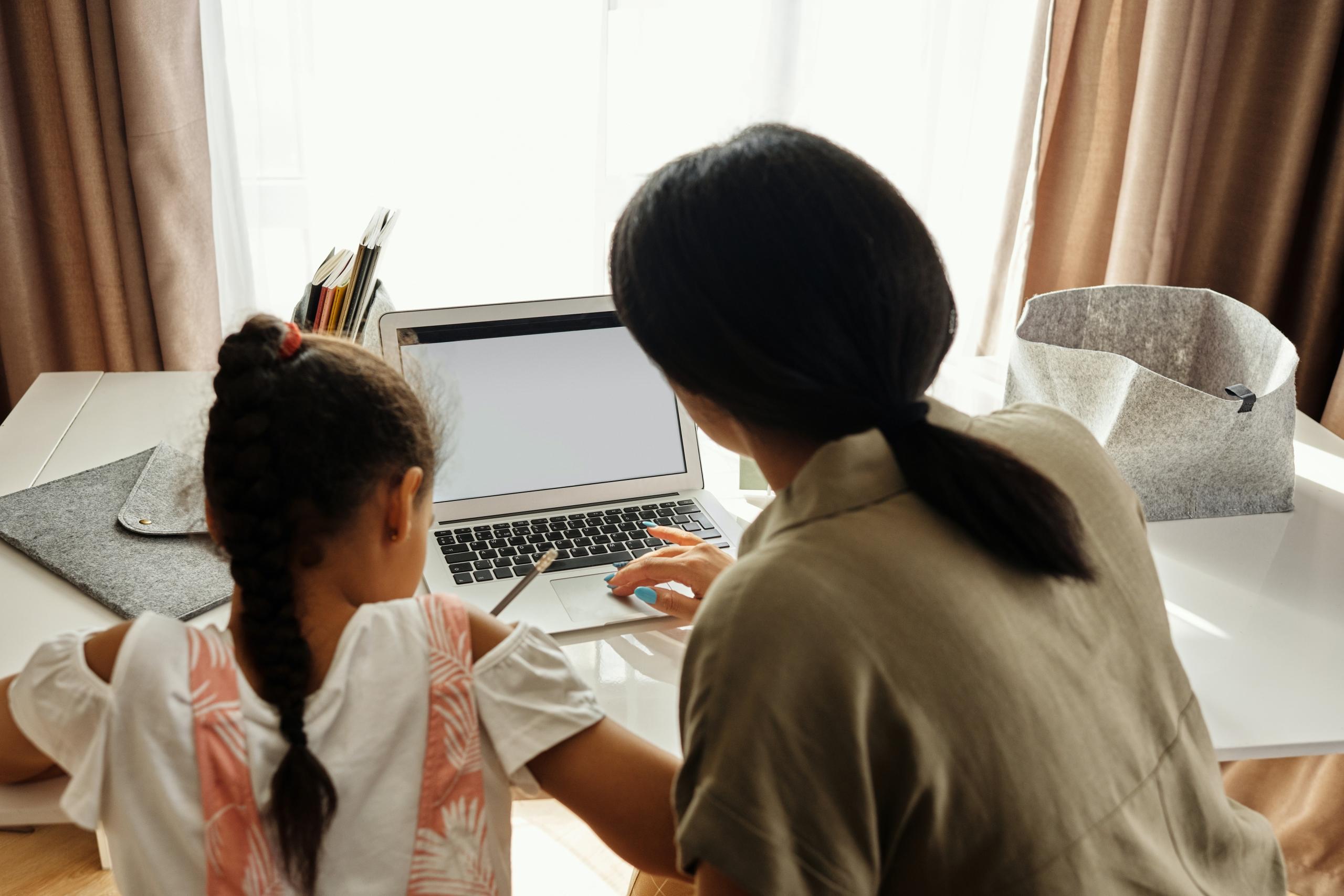 parent helping daughter with homework on computer