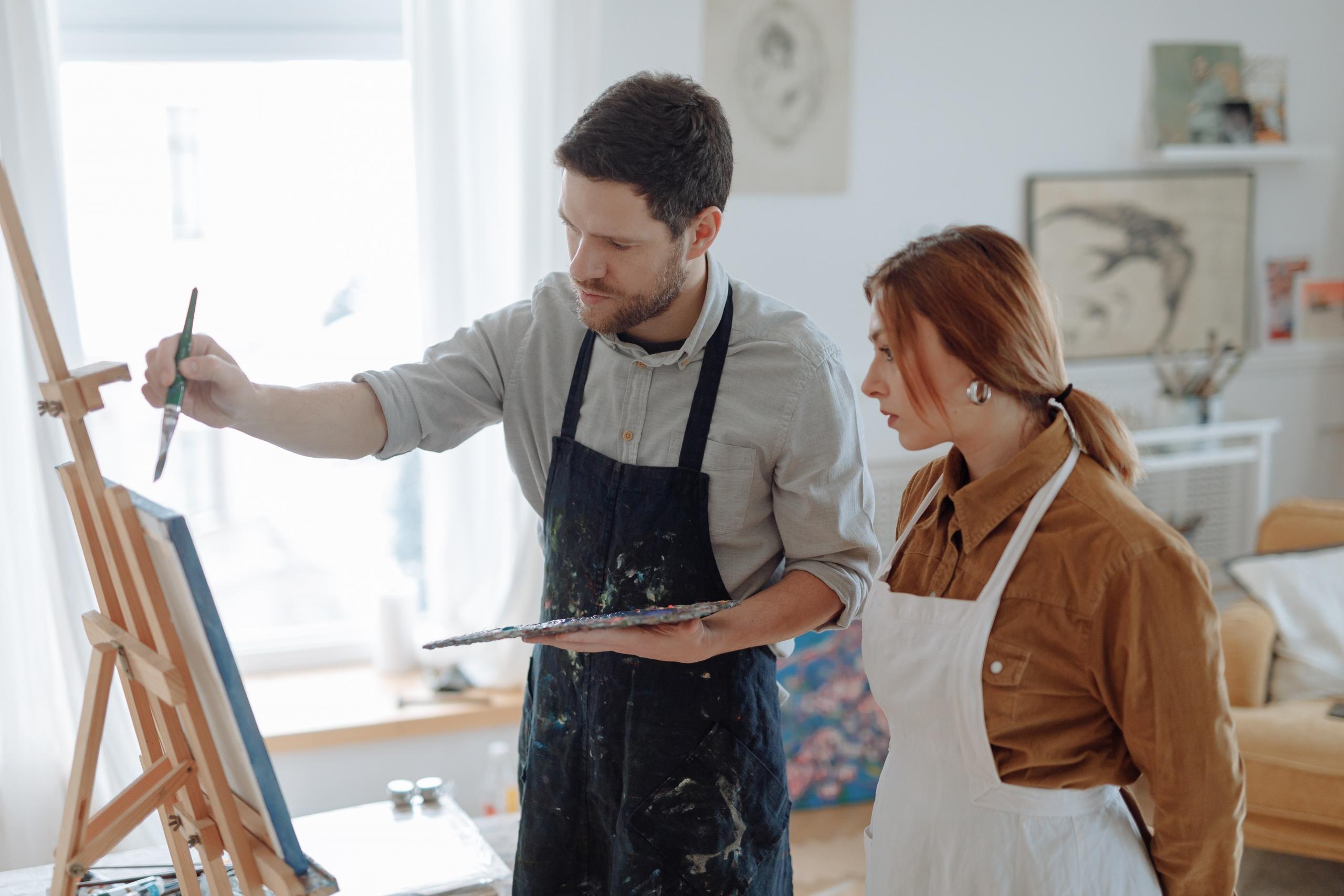 art teacher helping student paint using easel