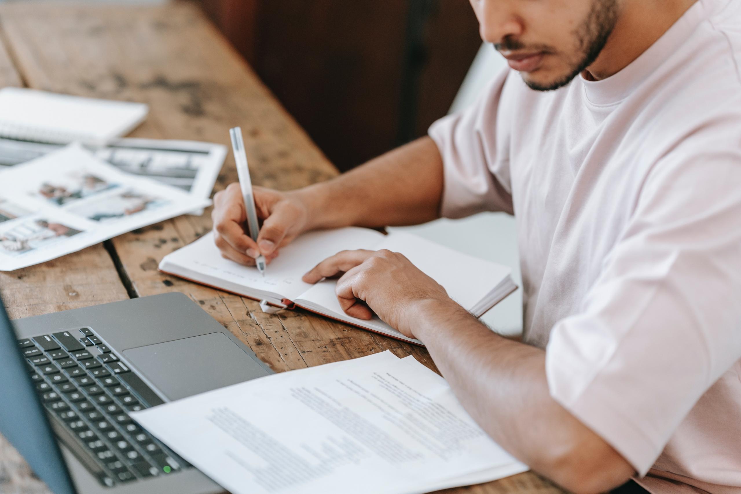 teenager doing homework with laptop and notebook