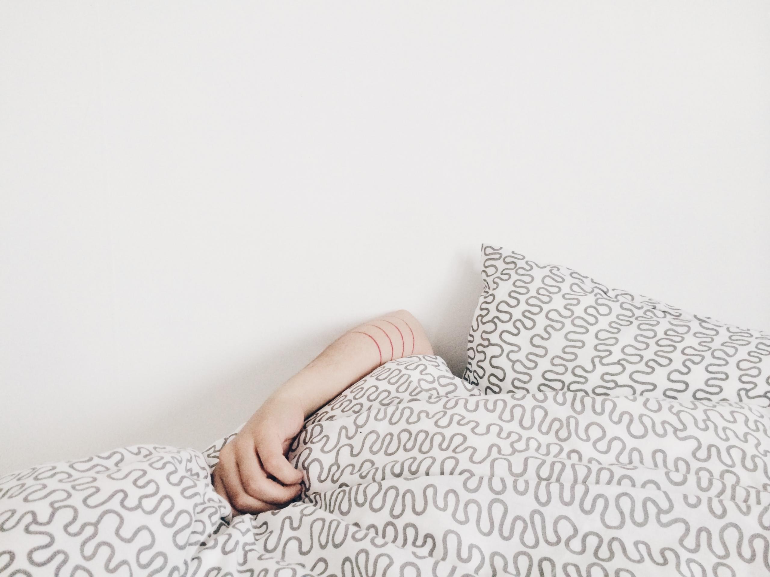 person sleeping with covers pulled over head