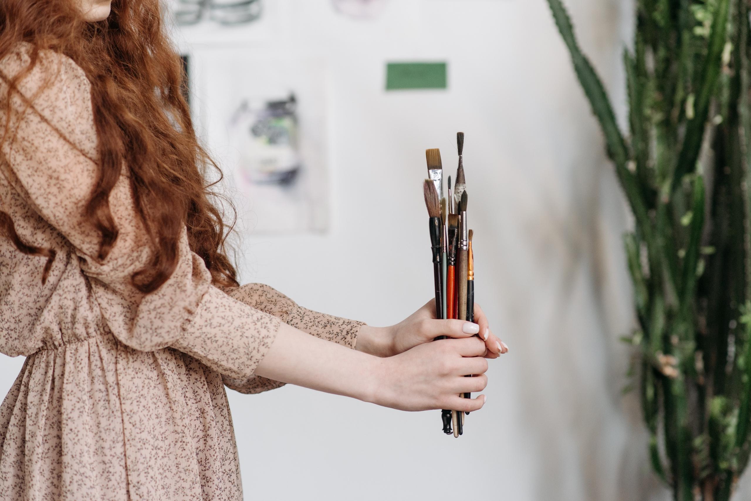 woman in art studio with an assortment of paintbrushes
