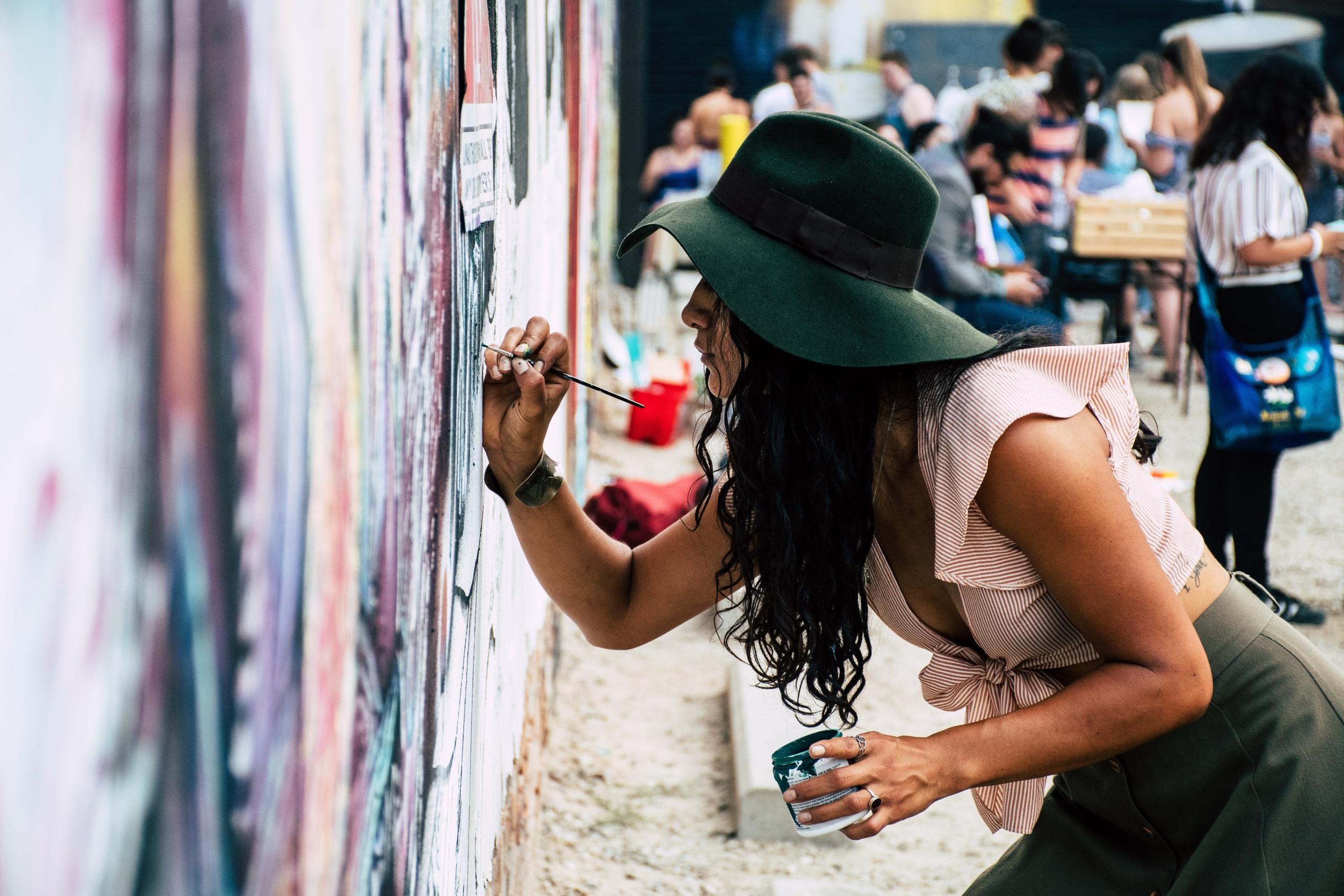 woman creating artwork on outdoor wall