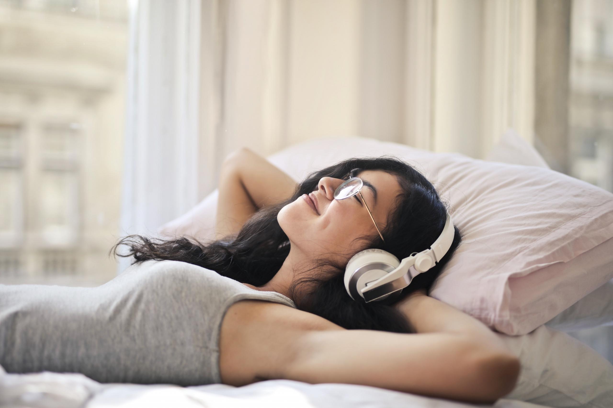 girl wearing headphones and reclined on bed