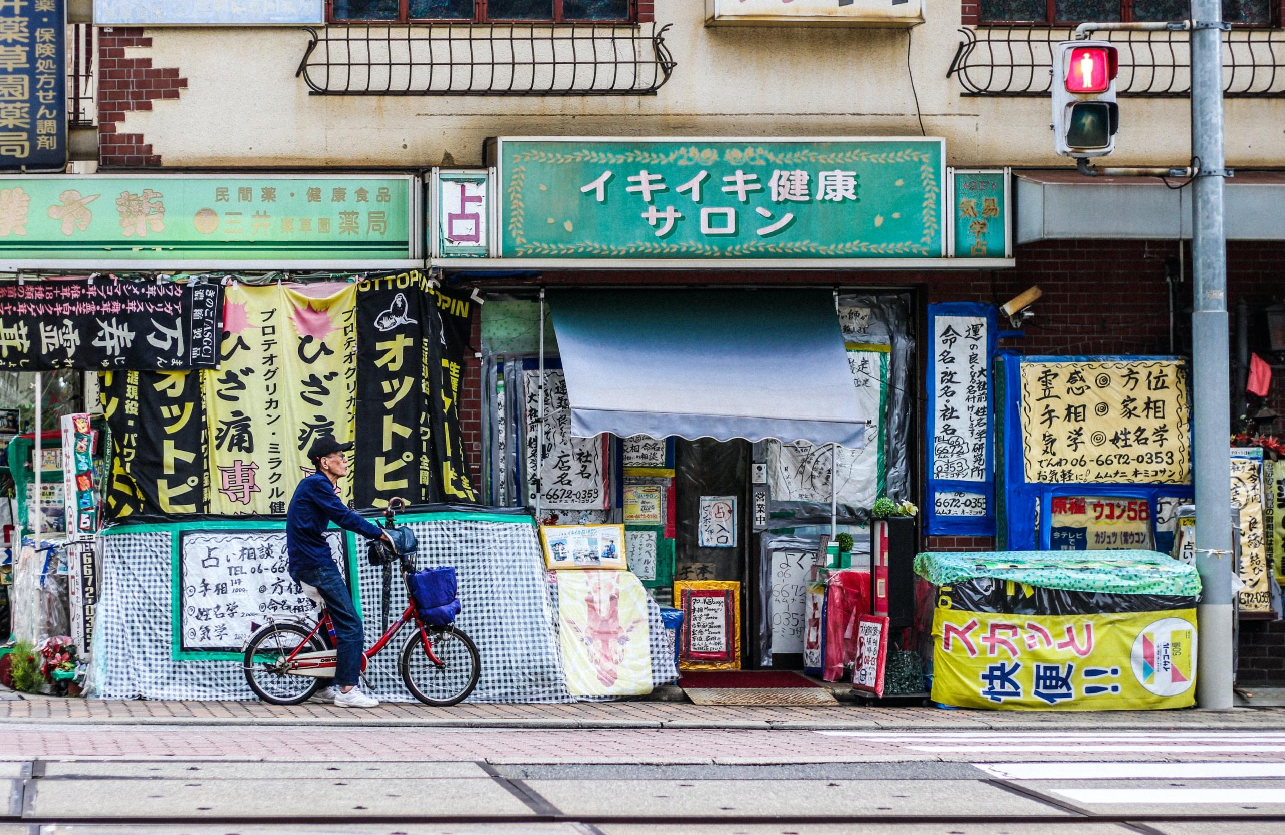 man cycling past shop in Japan