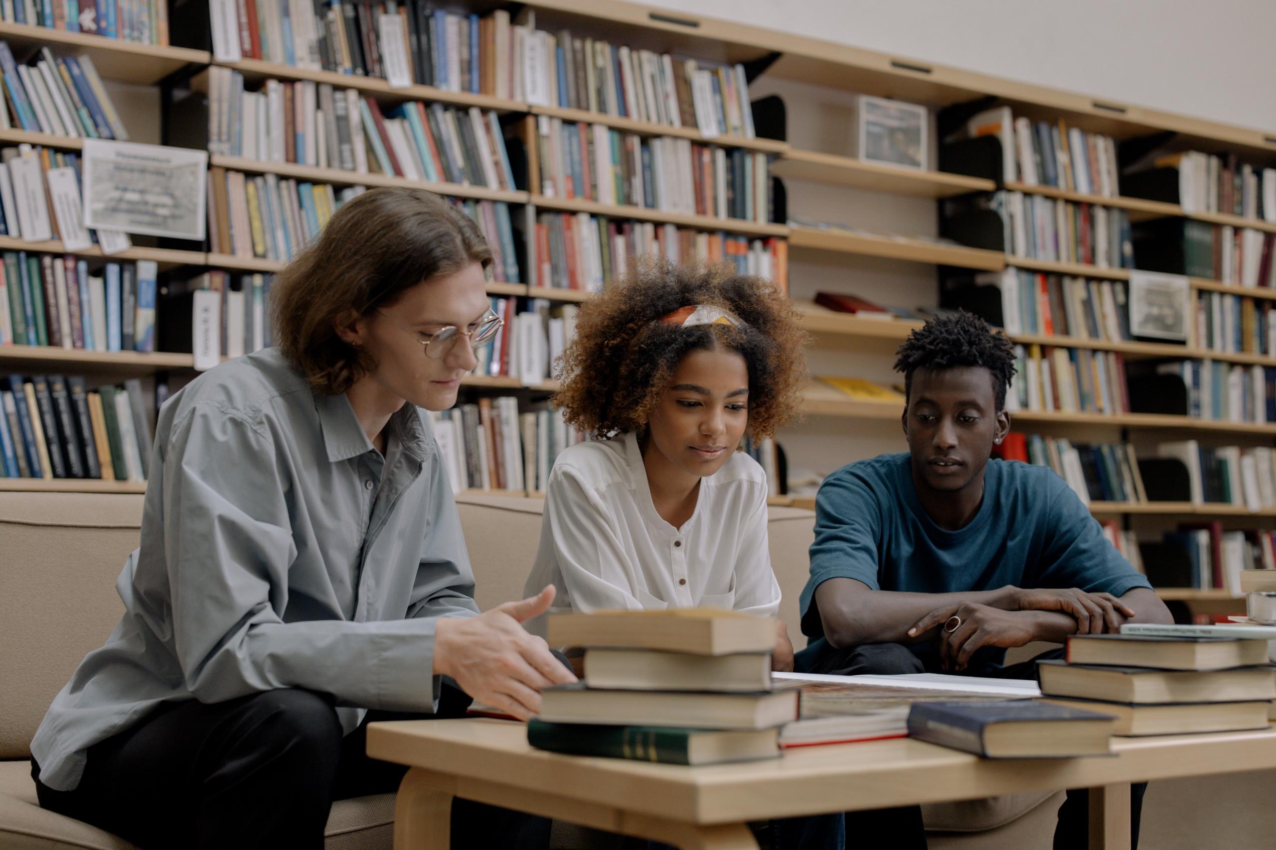 three students studying together in library