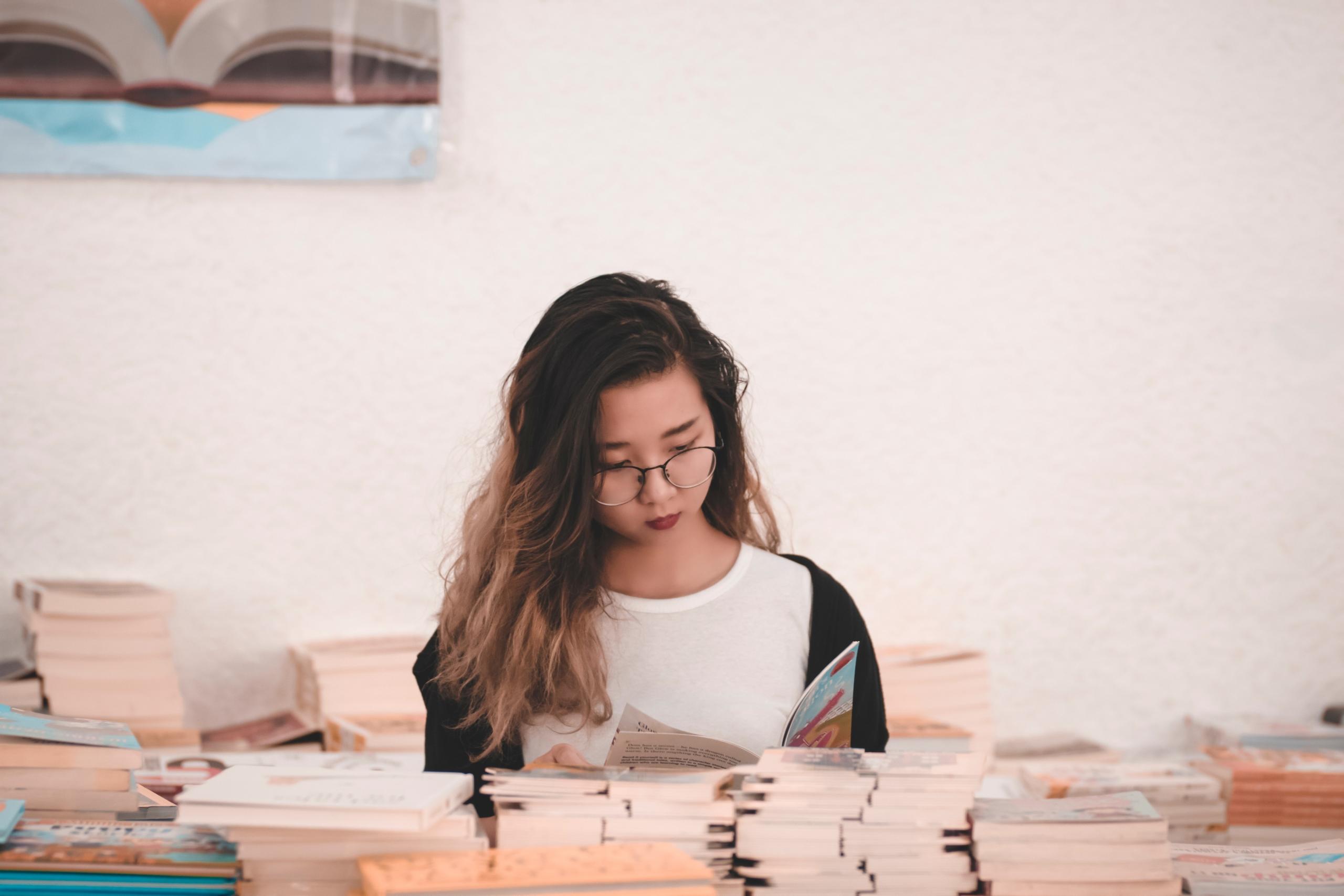 teen surrounded by stacks of books in bookshop