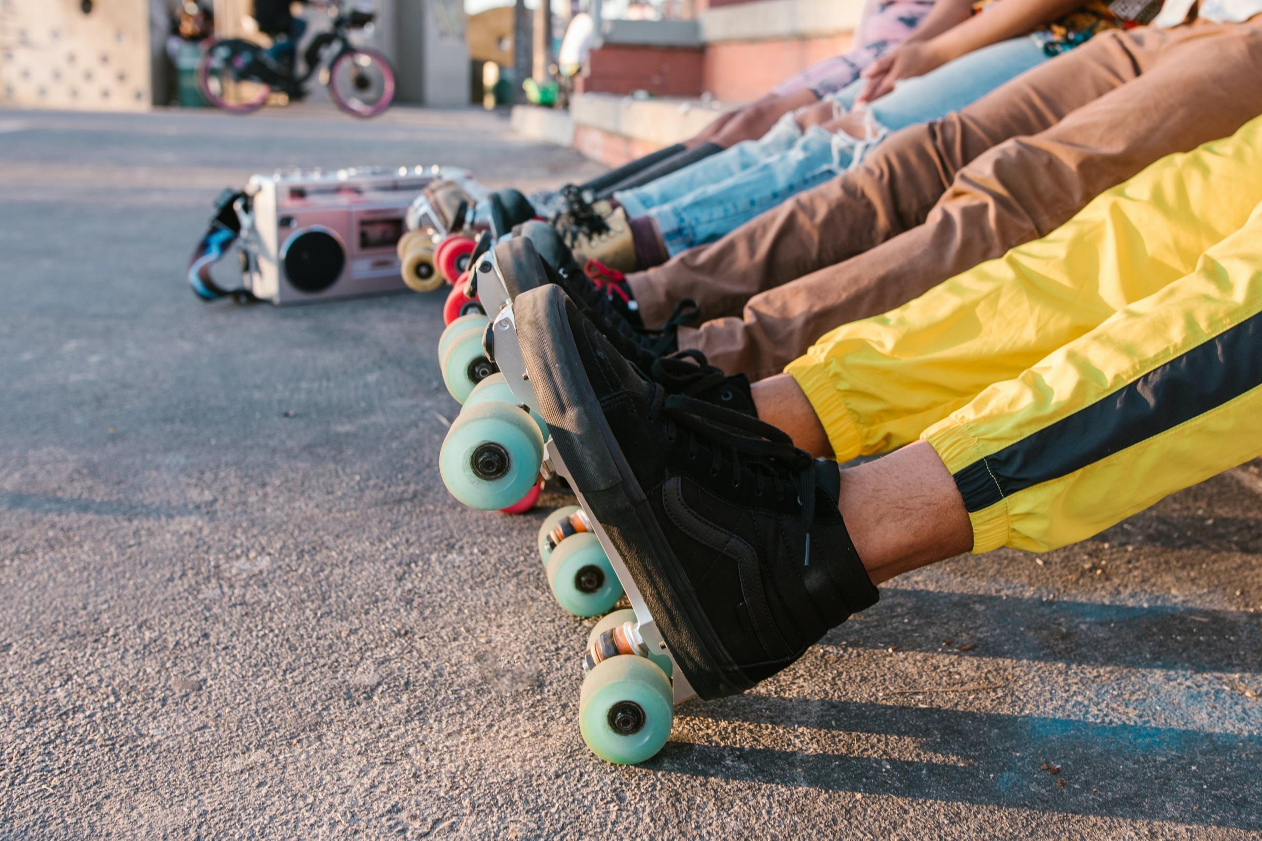 teens in roller skates seated with legs stretched out in front of them
