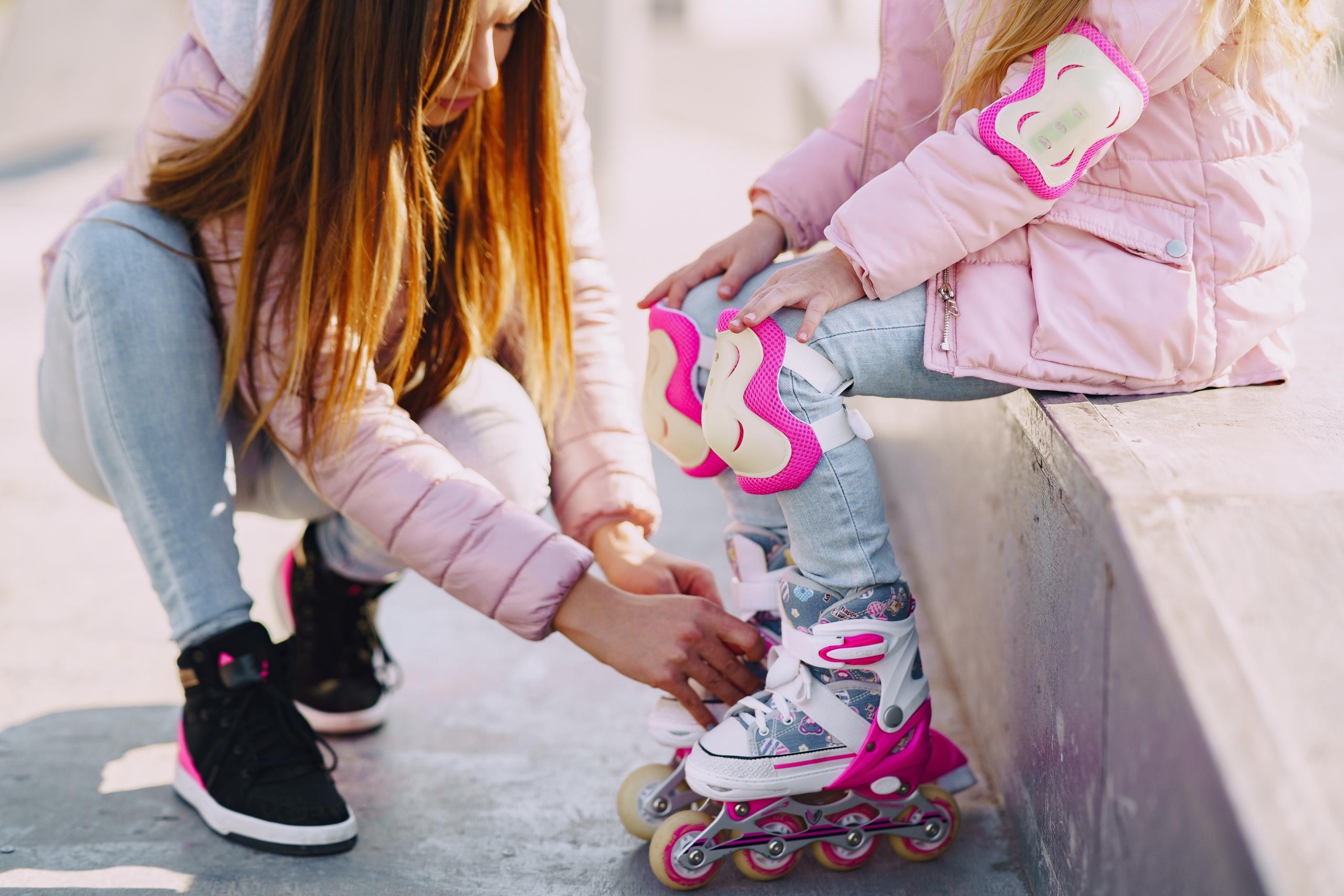 mom helping child put rollerblades on