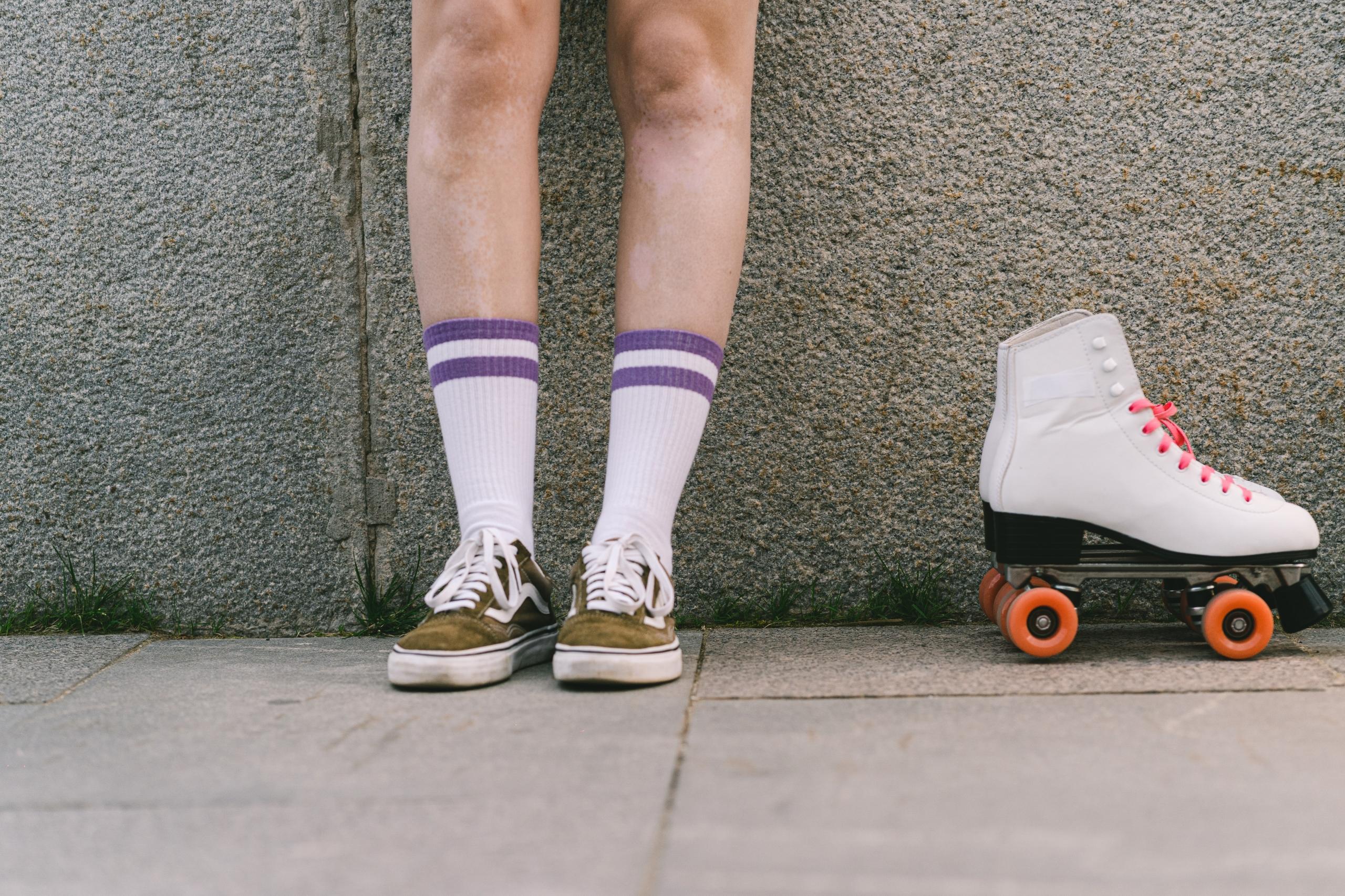 person standing against wall with a pair of white roller skates