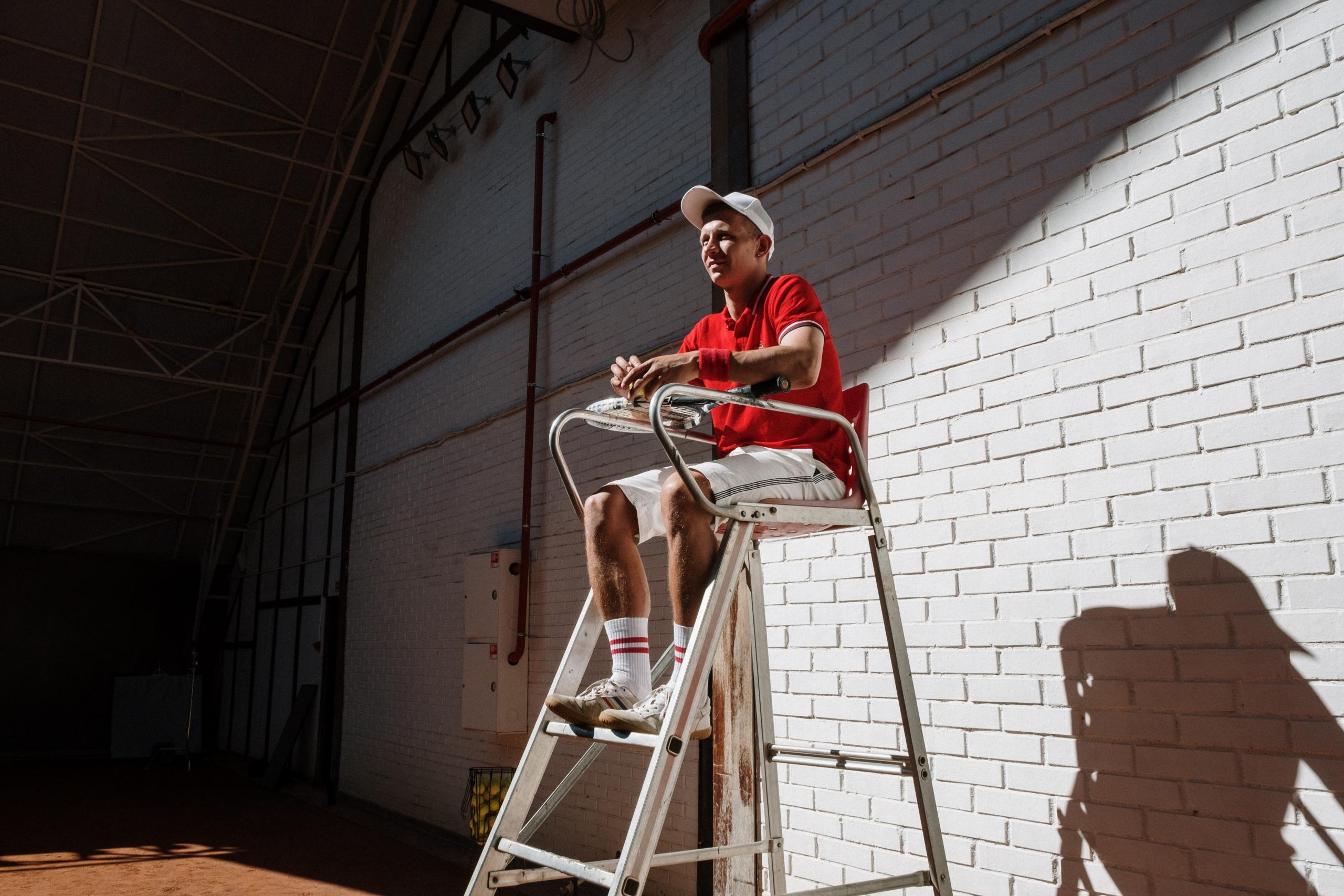 umpire seated on chair on beside tennis court