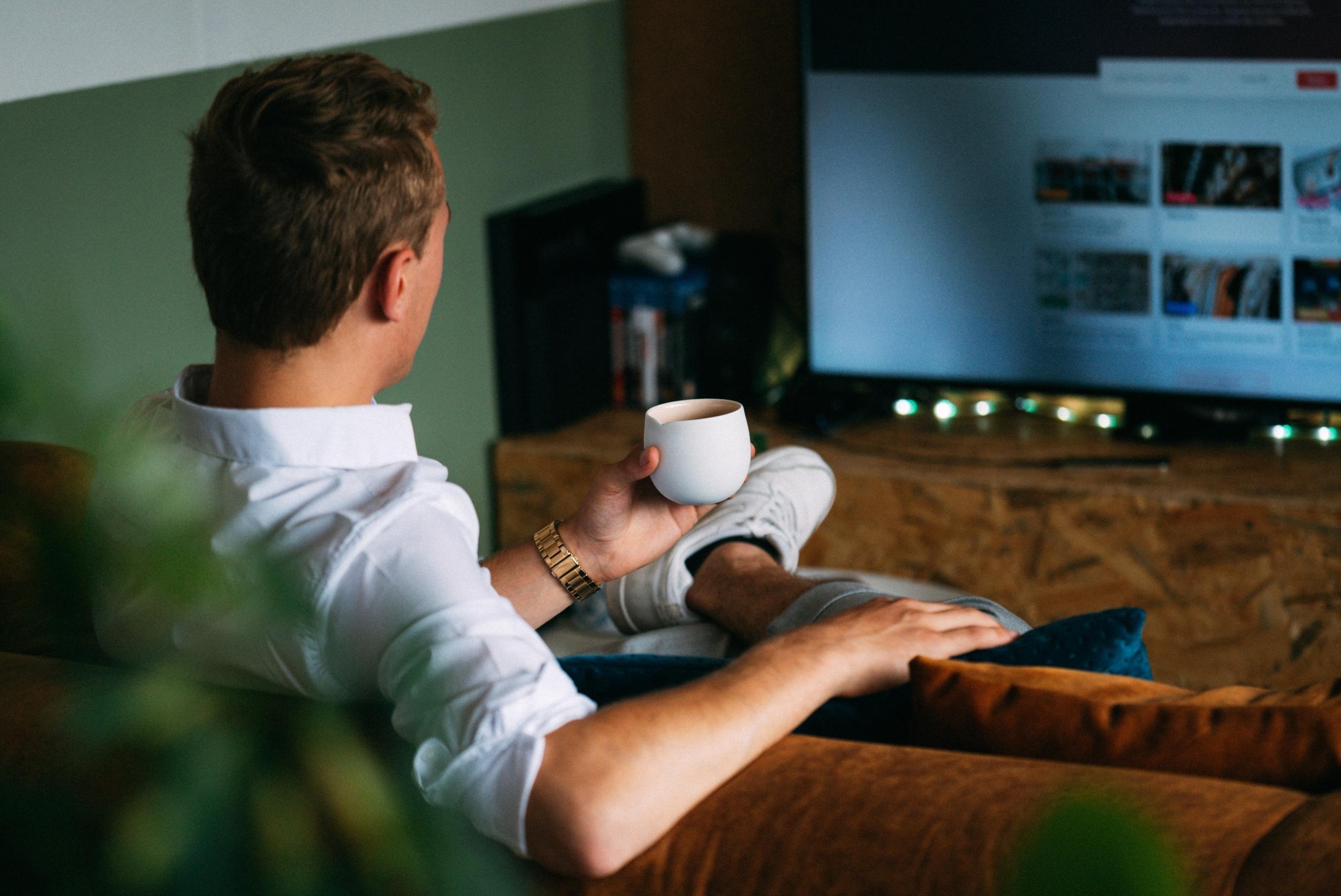 man sitting on couch in front of television